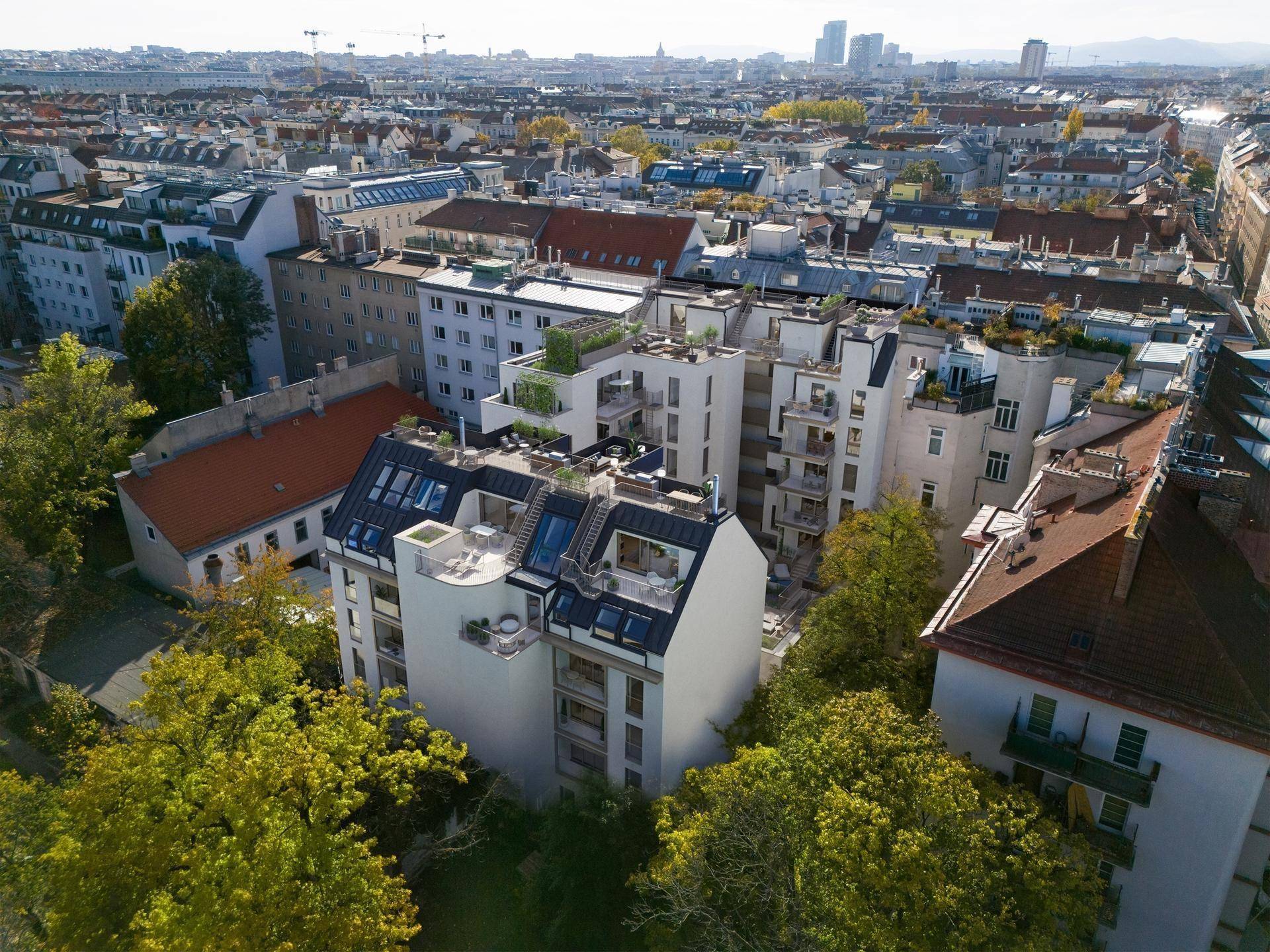 Luftaufnahme eines modernen Wohnkomplexes mit Dachterrassen und Balkonen in städtischer Umgebung.
