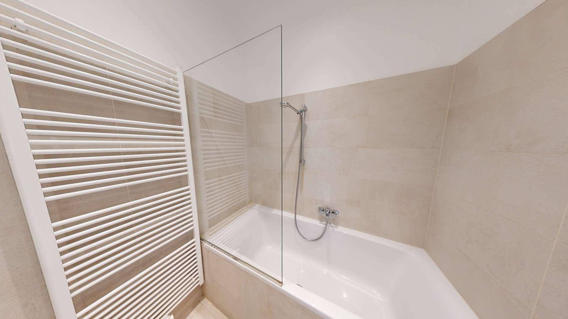 Modernes Badezimmer mit Badewanne, Duschabtrennung und beheiztem Handtuchhalter.