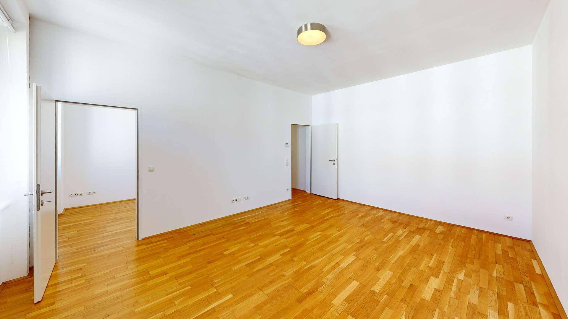 Geräumiger Wohnbereich mit hellem Parkettboden und weißen Wänden, bereit zur individuellen Gestaltung.