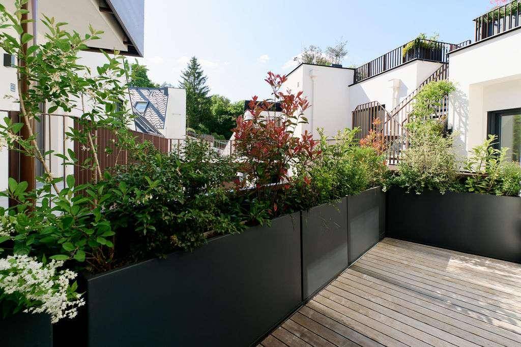 Attraktive Dachterrasse mit Holzdeck und begrünten Pflanzkübeln für entspannte Stunden.