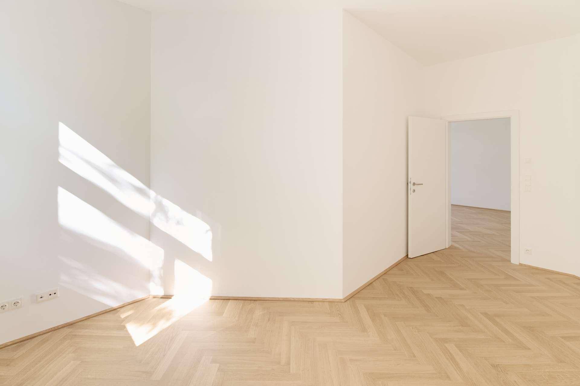 Sonniges Zimmer mit Fischgrätparkett, das von natürlichem Licht durchflutet wird.