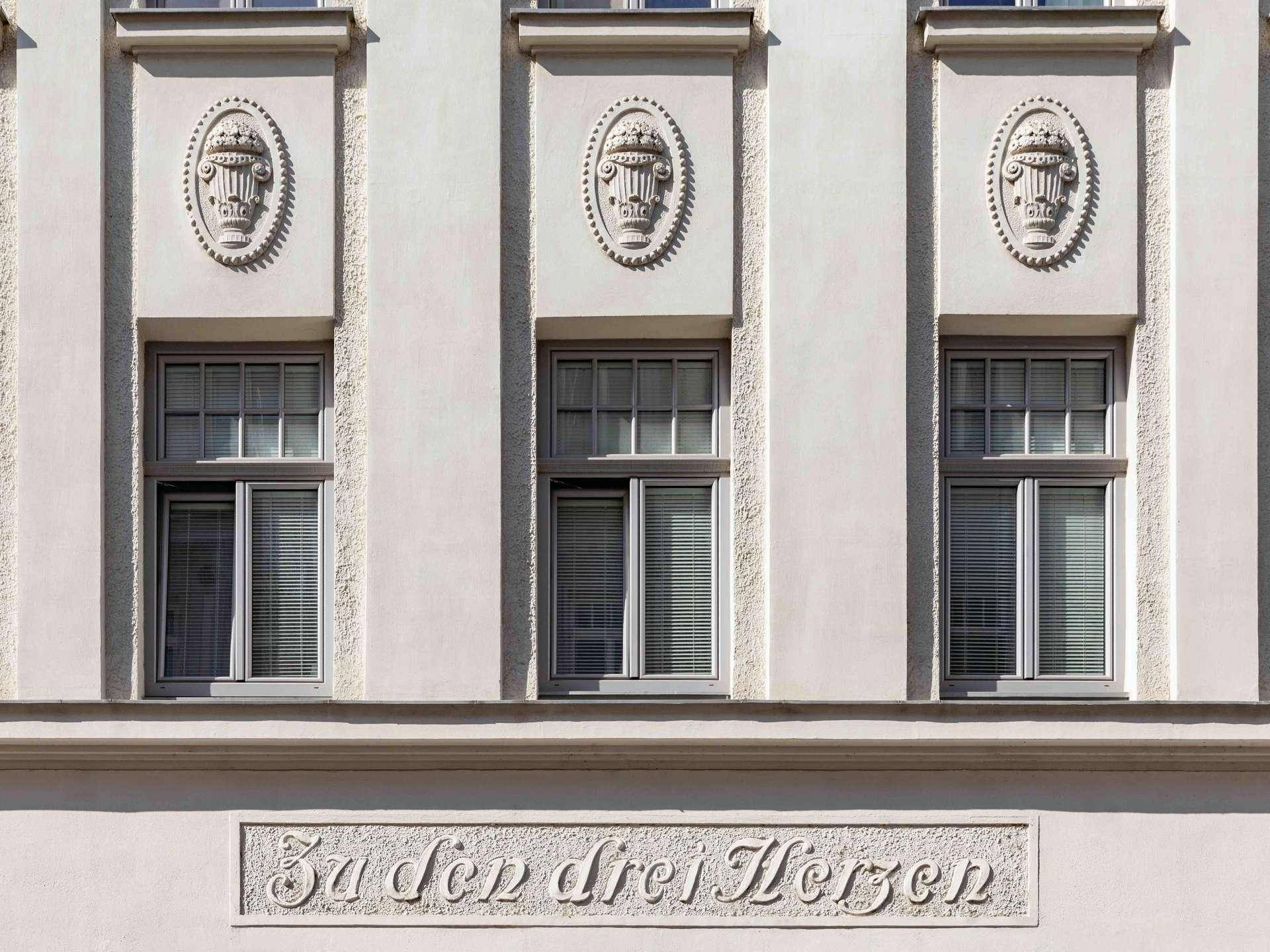Detailansicht der verzierten Fenster und Fassadenelemente eines historischen Gebäudes.
