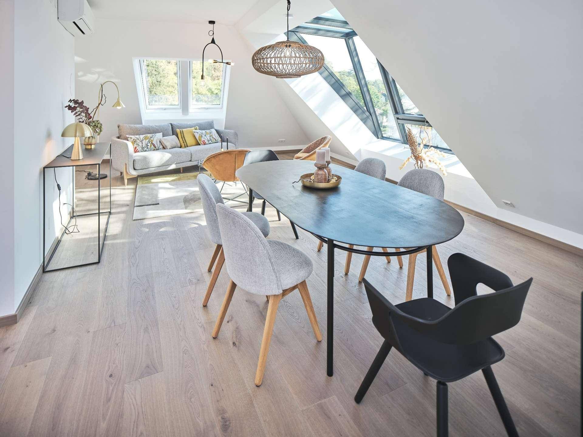 Geräumiger Wohn-Essbereich mit Holzboden, stilvoller Einrichtung und schrägen Decken mit Dachfenstern.