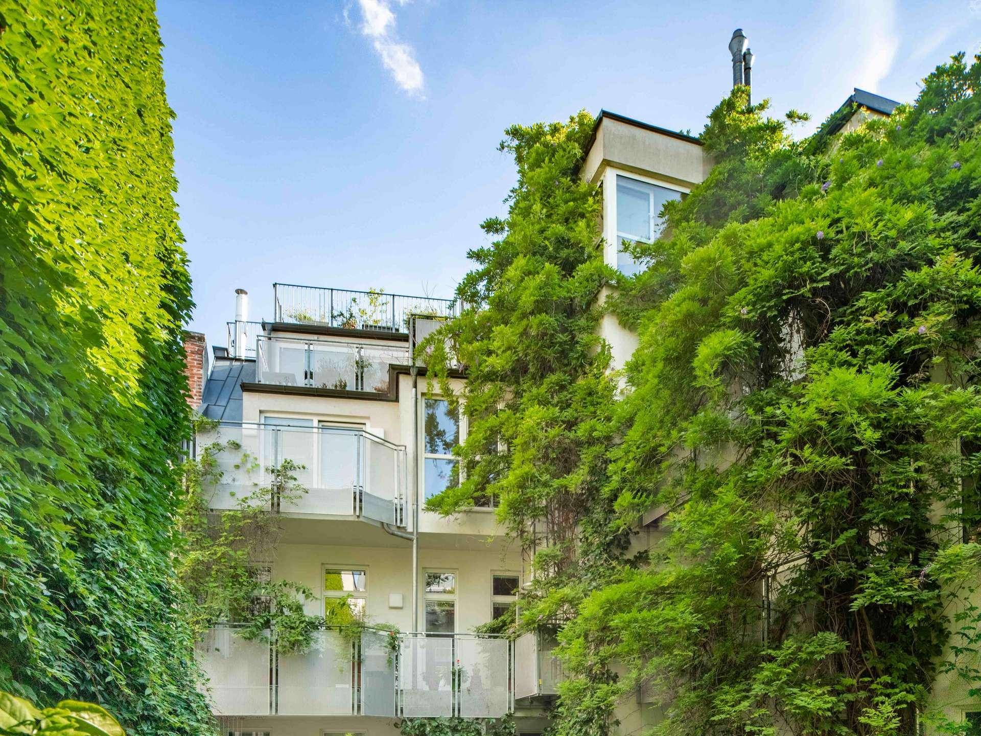 Grüne Rückfassade des Gebäudes mit mehreren Balkonen und üppiger Vegetation.