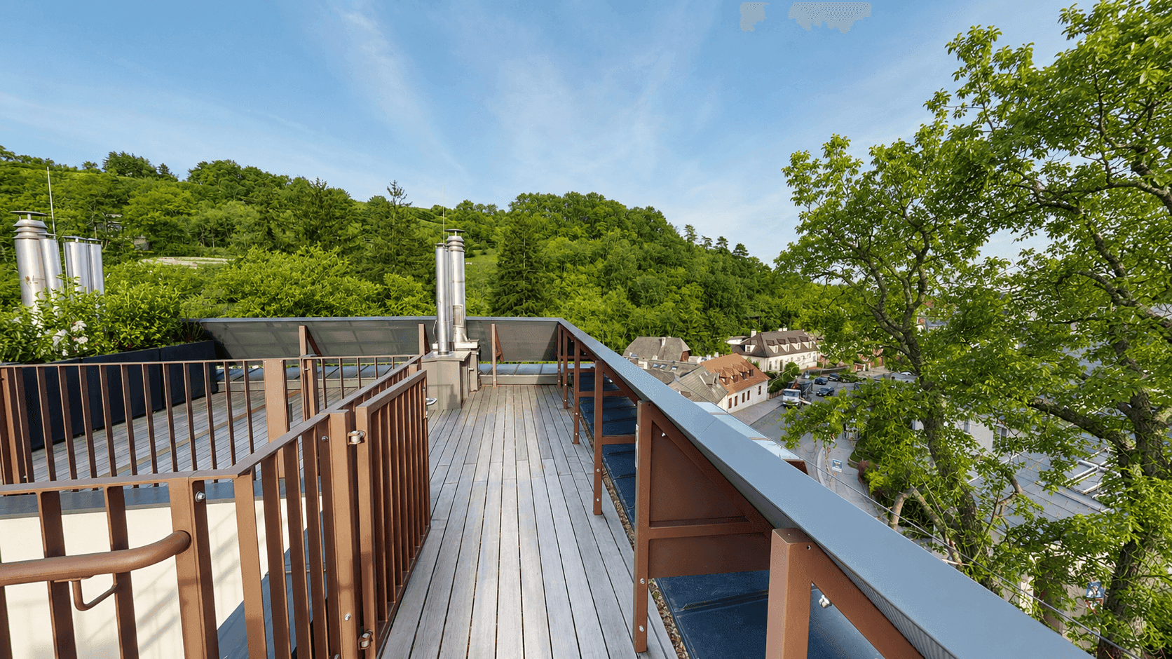 Geräumige Dachterrasse mit Holzboden und weitem Blick auf die grüne Umgebung und die Stadt.