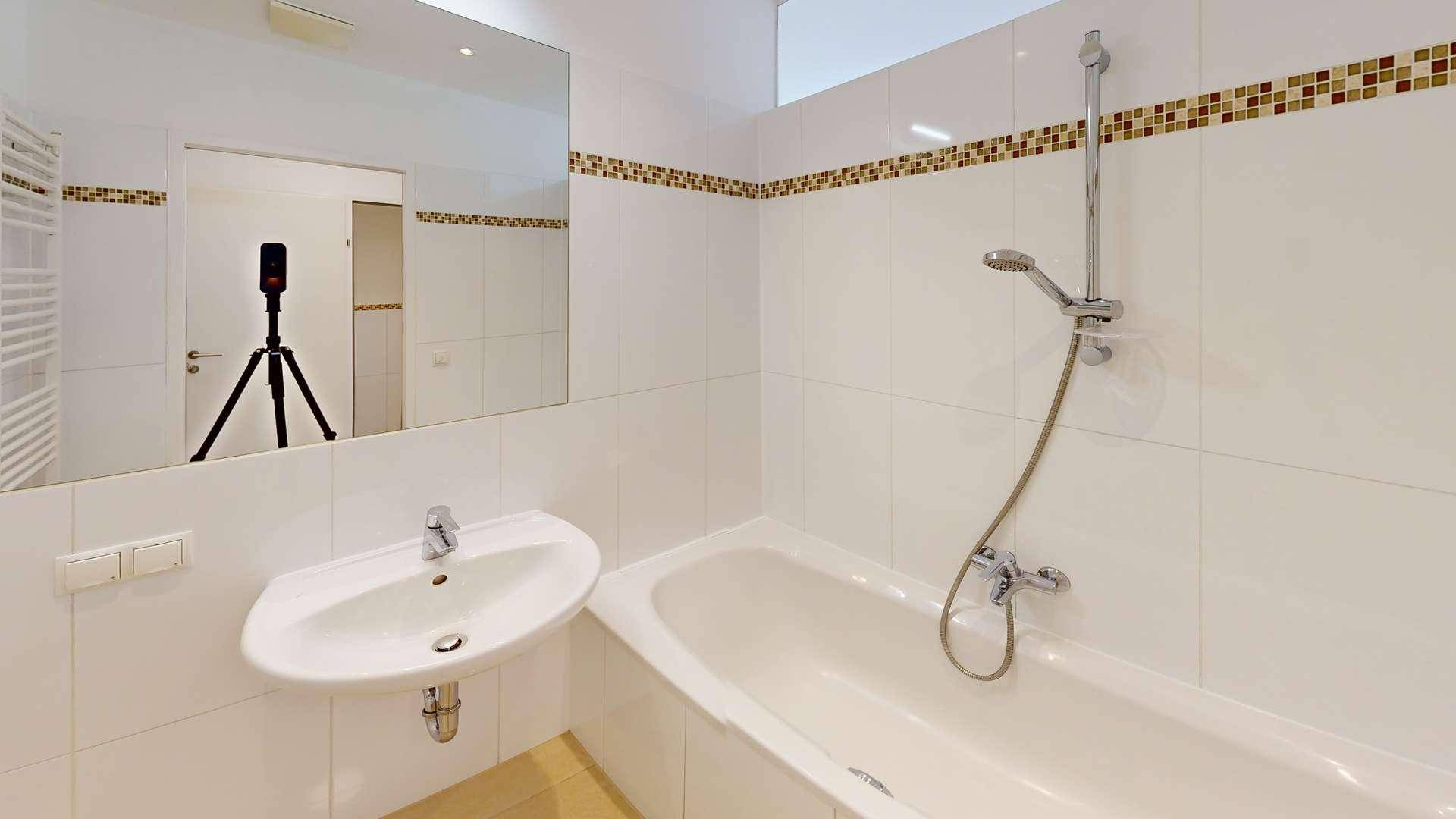 Modernes Badezimmer mit Badewanne, Dusche und weiß gefliesten Wänden, inklusive Handtuchheizkörper.