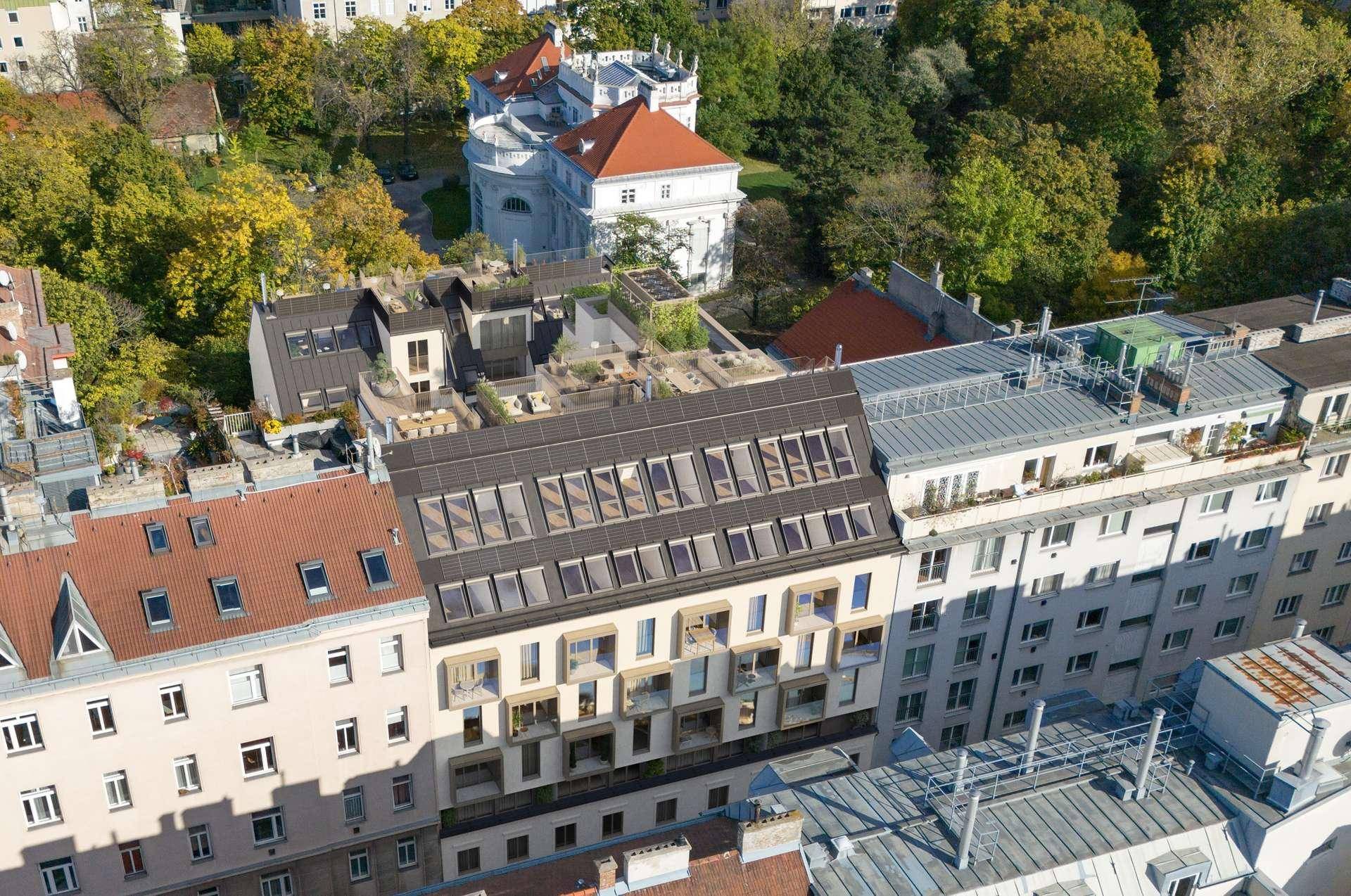 Luftaufnahme eines modernen Wohngebäudes mit Dachterrassen und umliegenden historischen Gebäuden.