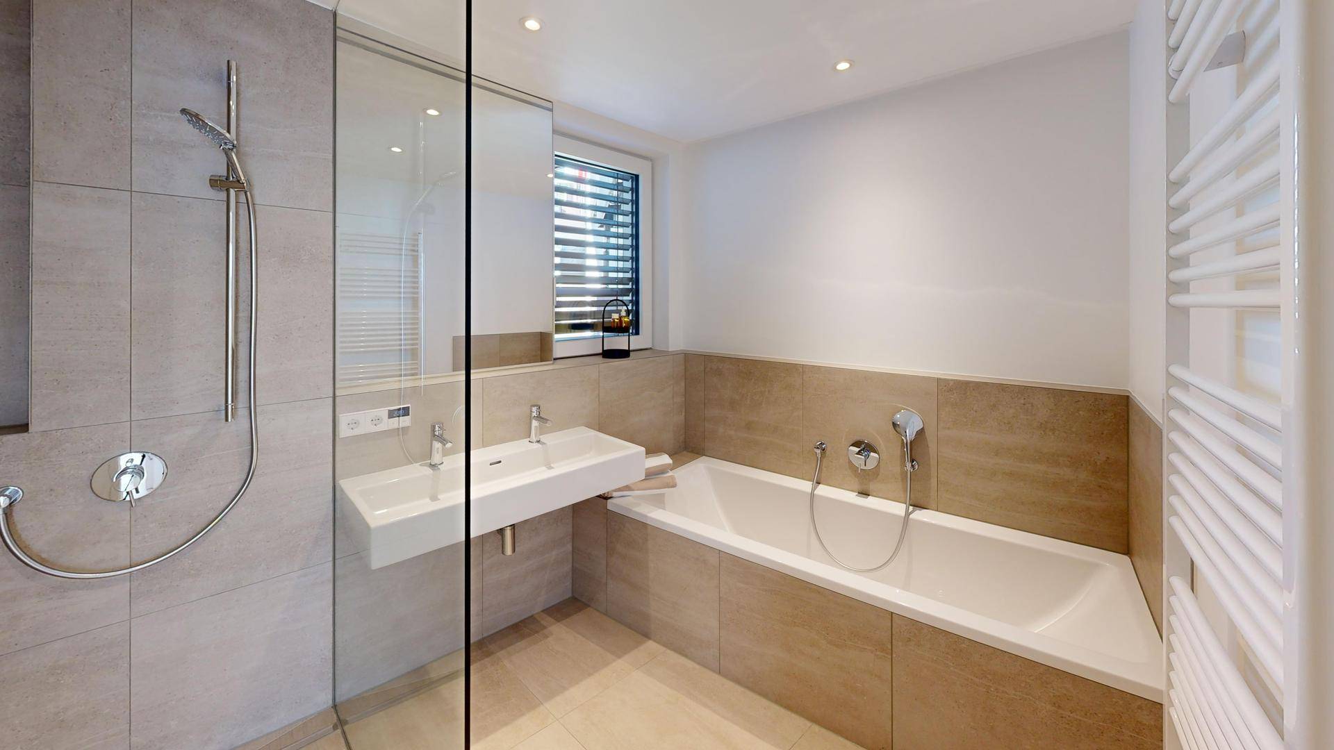 Modernes Badezimmer mit Doppelwaschbecken, Badewanne und ebenerdiger Dusche in hellen Fliesen.