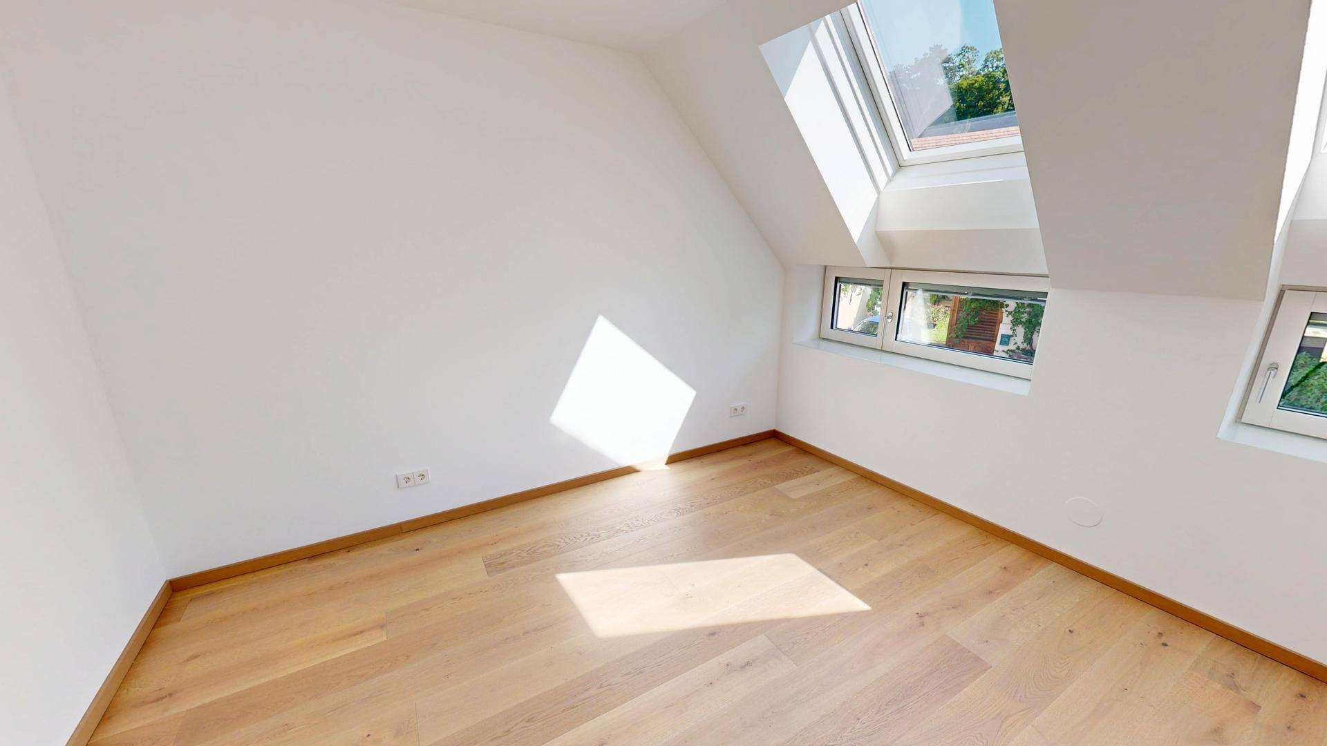 Helles Schlafzimmer mit Holzboden, Dachschrägen und großen Dachfenstern für viel Licht.