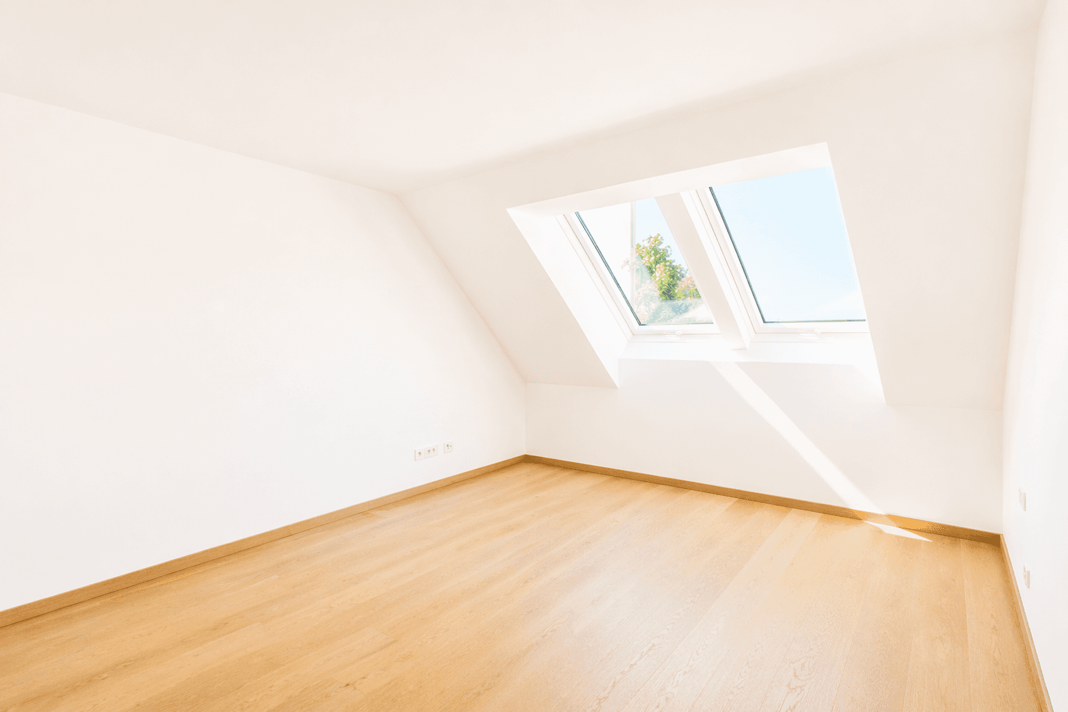Helles Zimmer mit Holzboden und großem Dachfenster, ideal als Schlaf- oder Arbeitszimmer.