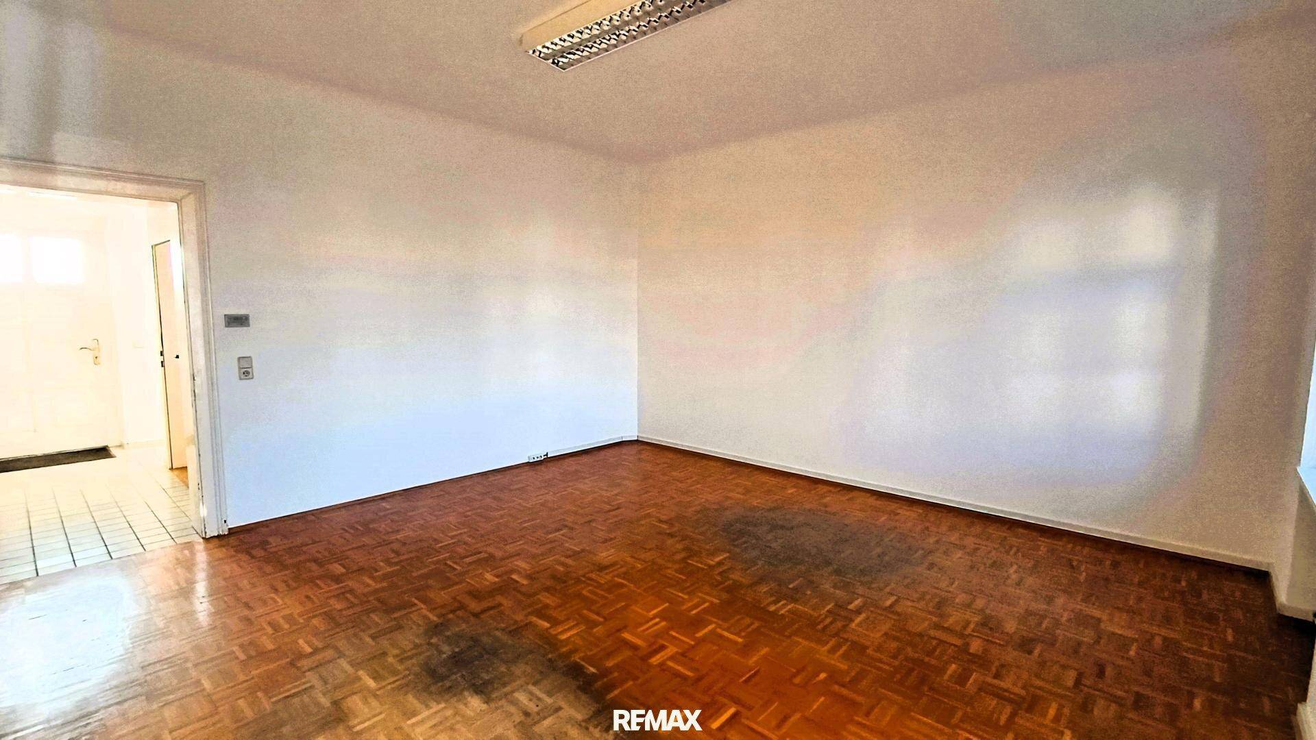 Leerer Raum mit Parkettboden und weiß gestrichenen Wänden, bereit zur individuellen Gestaltung.
