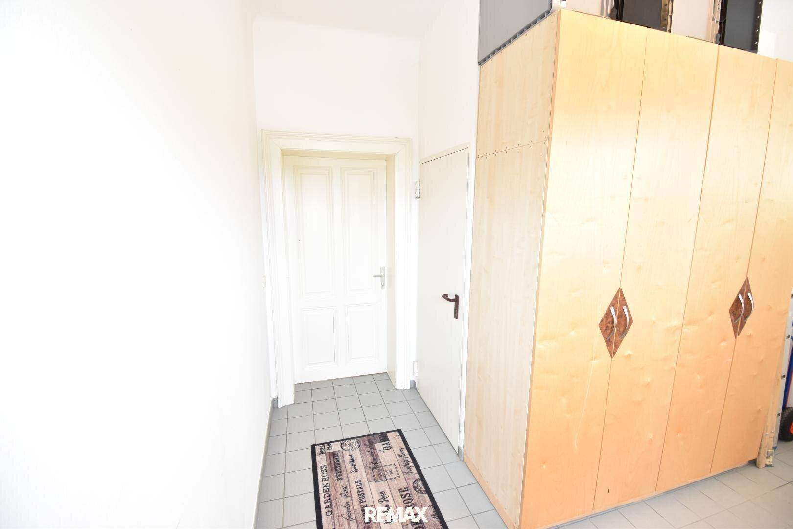 Eingangsbereich mit Fliesenboden und einem großen Holzschrank, der viel Stauraum bietet.