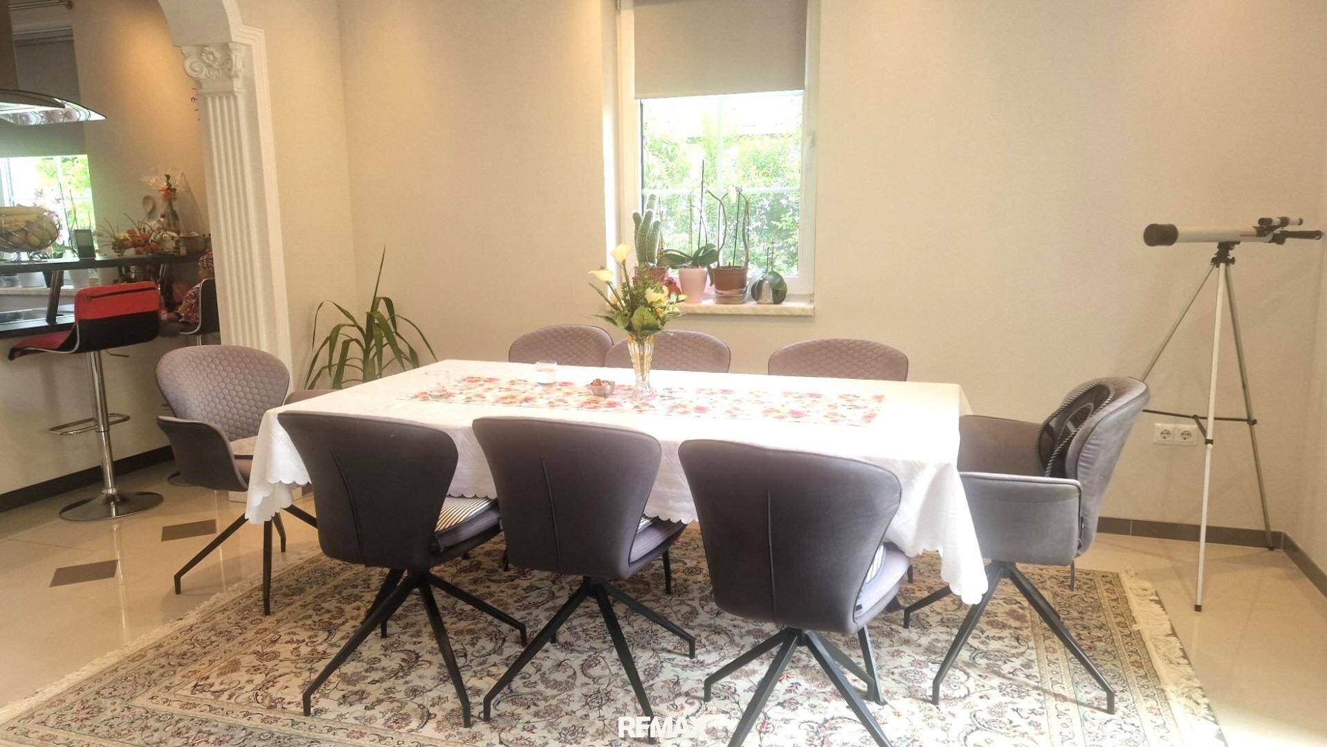 Heller Essbereich mit großem Tisch, modernen Stühlen und Blick ins Grüne.