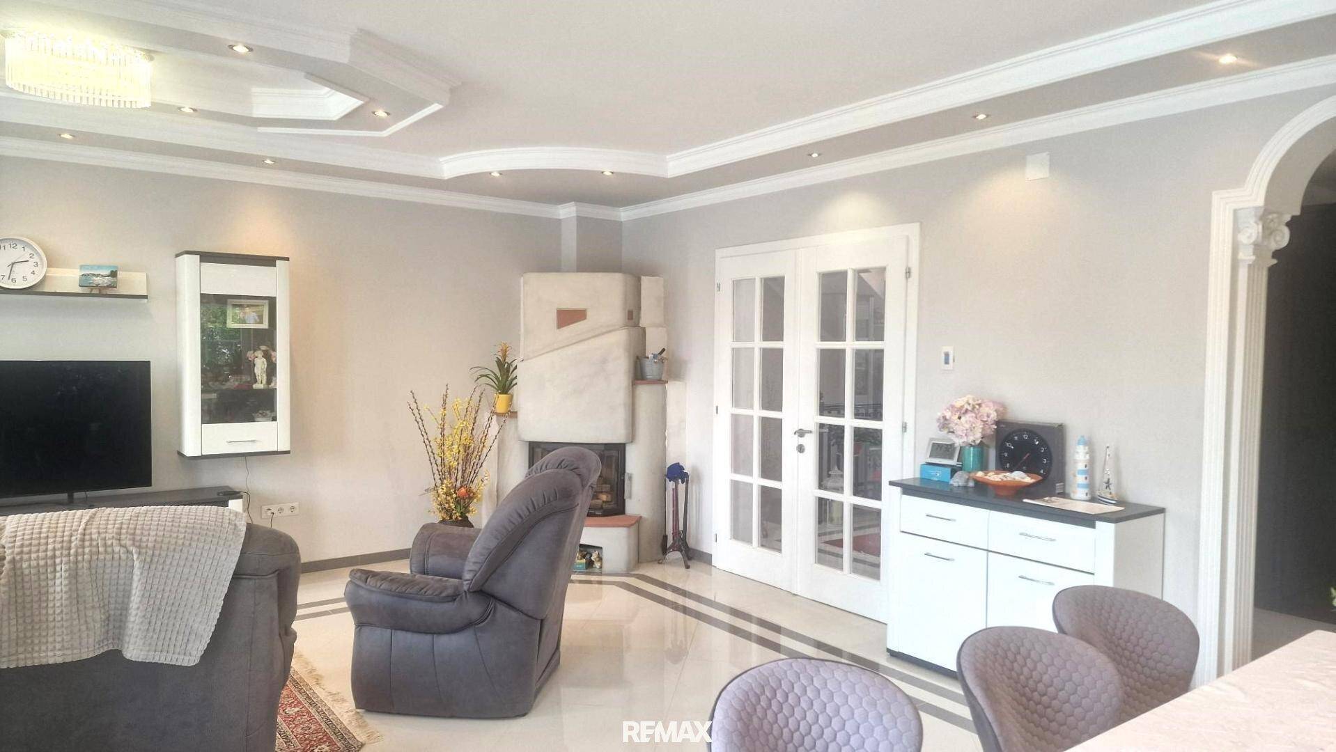 Helles Wohnzimmer mit Kamin, eleganten Stuckelementen und Fliesenboden.