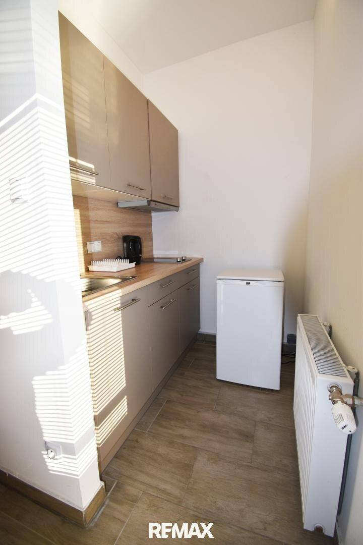 Funktionale Küchenzeile mit Oberschränken, Arbeitsplatte und kleinem Kühlschrank.