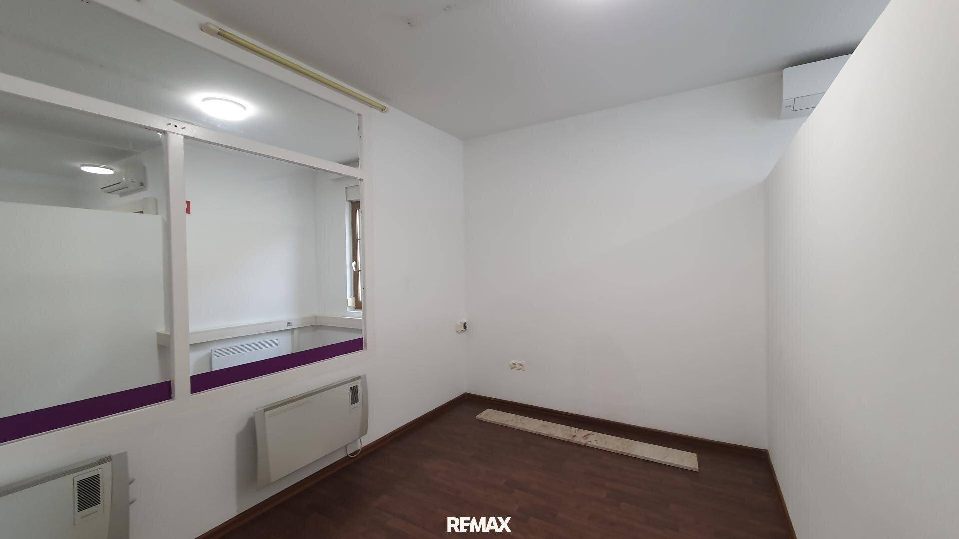 Heller Büroraum mit Laminatboden und einer internen Glaswand, die eine offene Raumgestaltung ermöglicht.