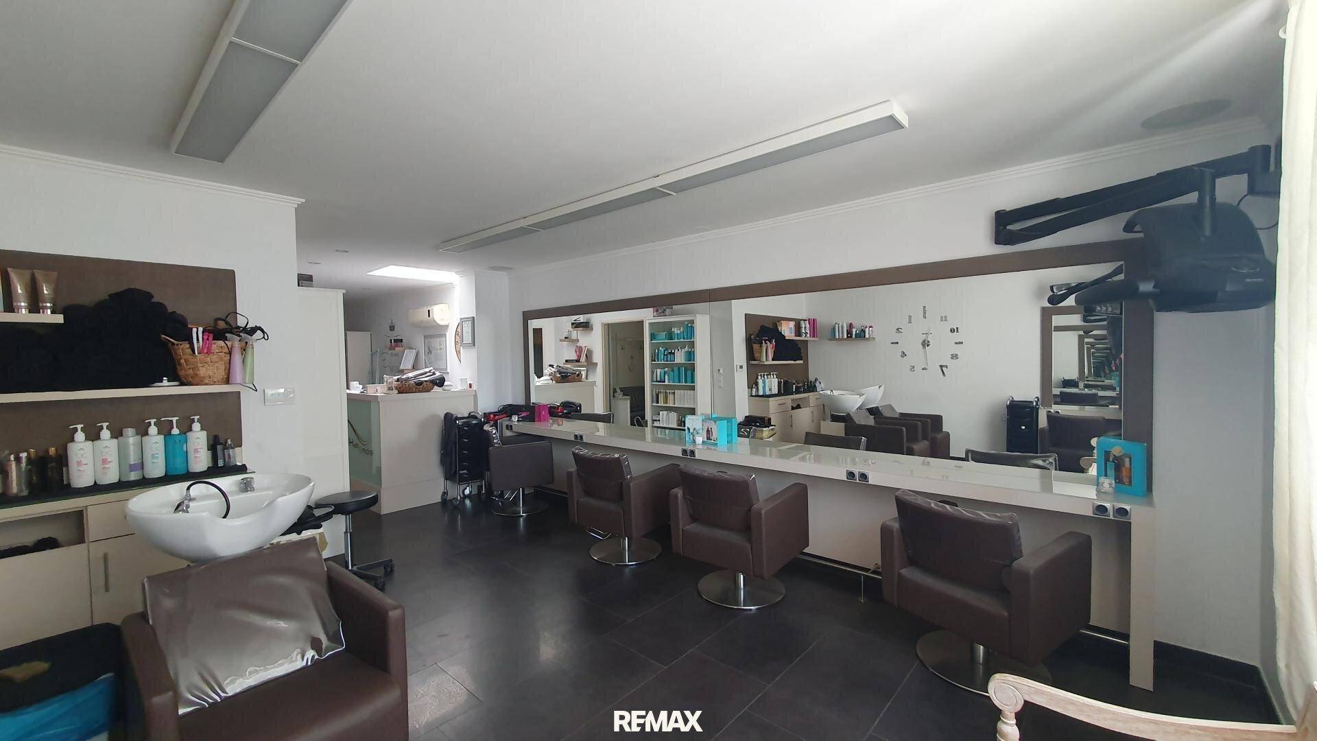 Geräumiger Friseursalon mit mehreren Styling-Stationen, großen Spiegeln und Regalen voller Pflegeprodukte.