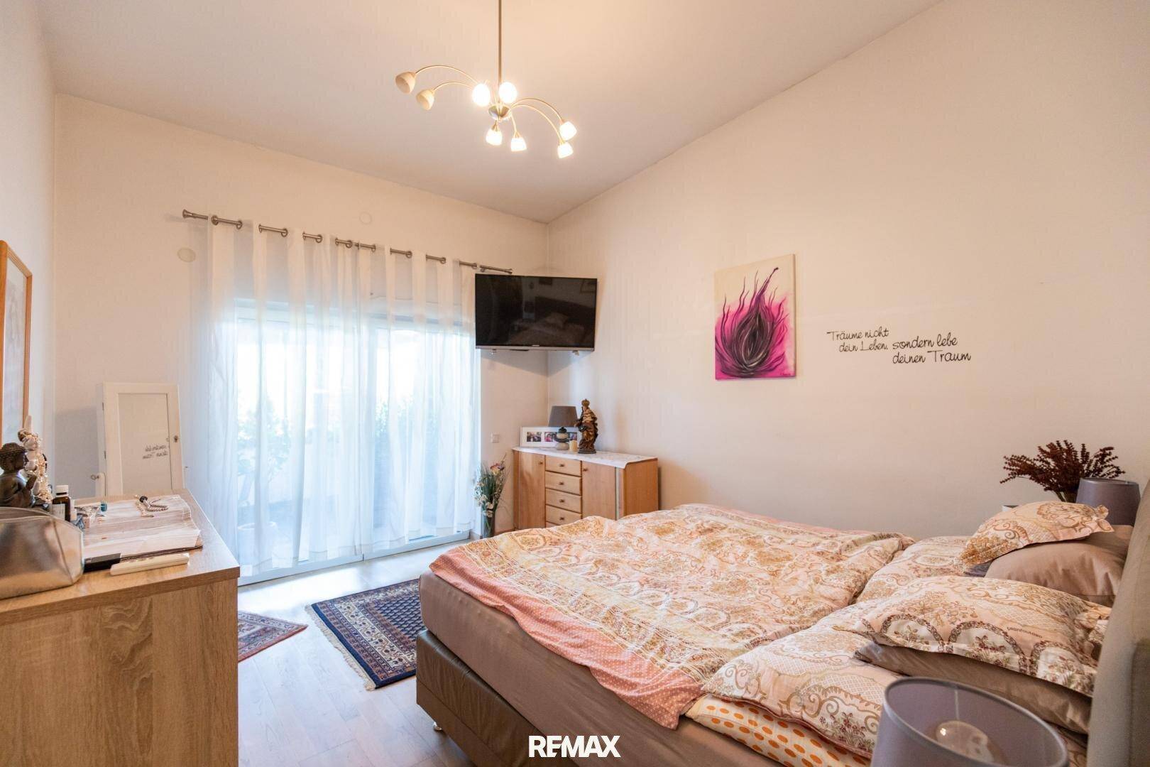 Gemütliches Schlafzimmer mit Doppelbett, Holzboden und Zugang zum Balkon, hell und freundlich.
