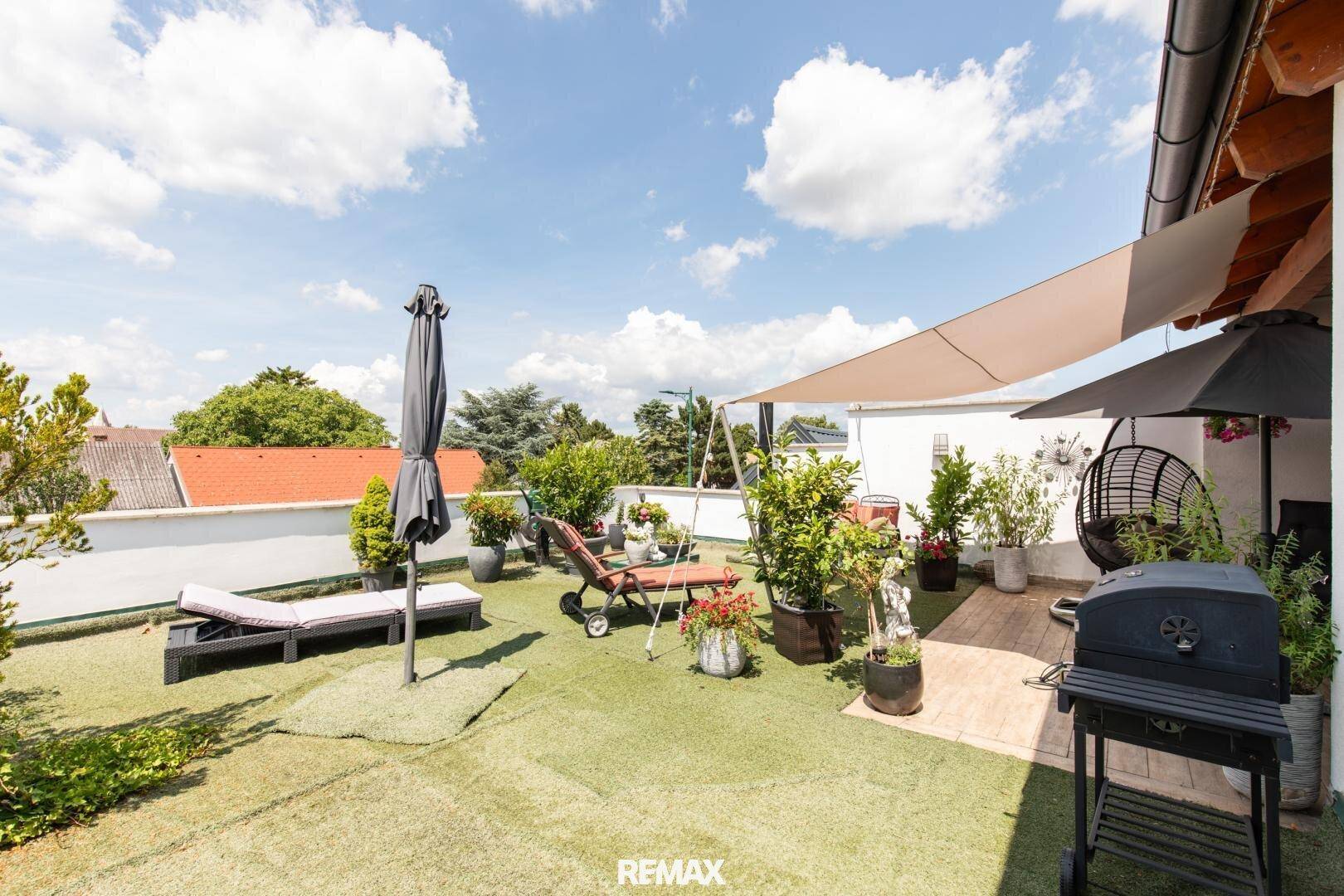 Große Dachterrasse mit Kunstrasen, Sonnenliegen und Grillbereich, perfekt für sonnige Tage.