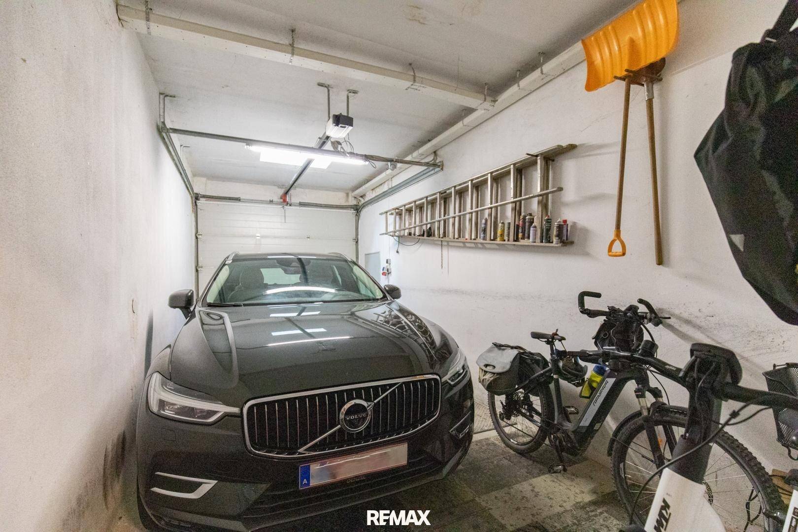 Geräumige Garage mit Platz für ein Auto und Fahrräder, ausgestattet mit einem automatischen Tor.