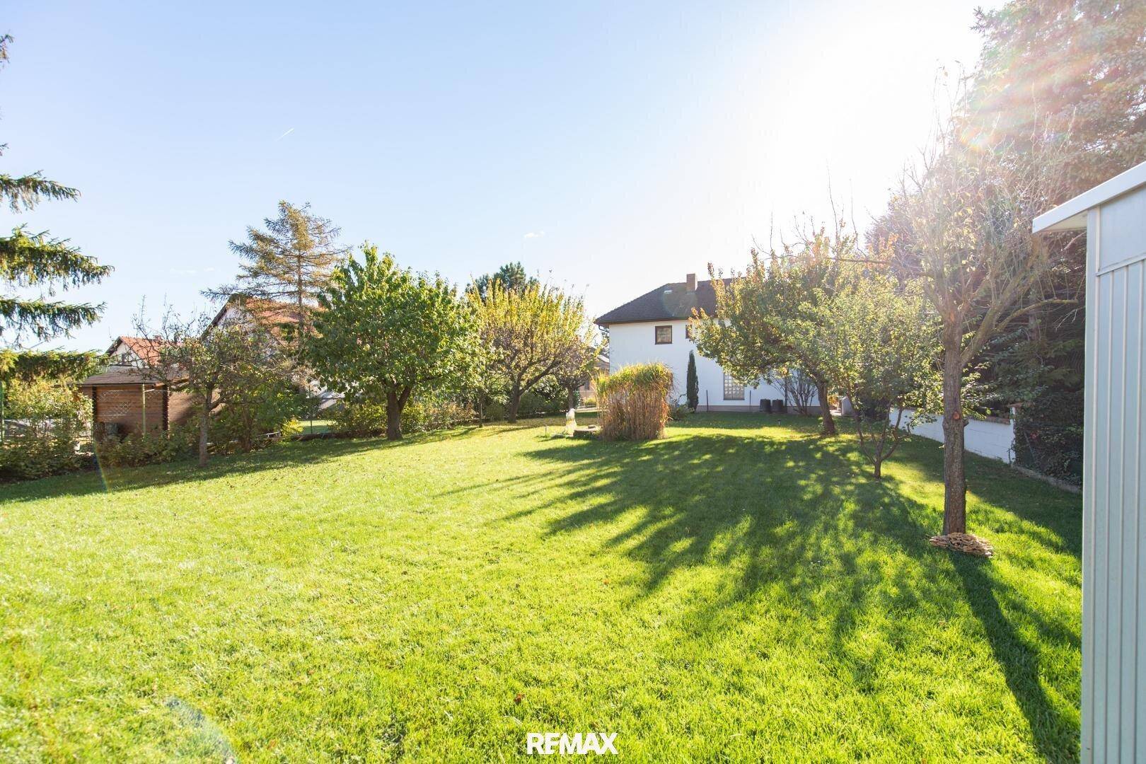 Großer, gepflegter Garten mit Rasenfläche und Bäumen, ideal für Erholung im Freien.