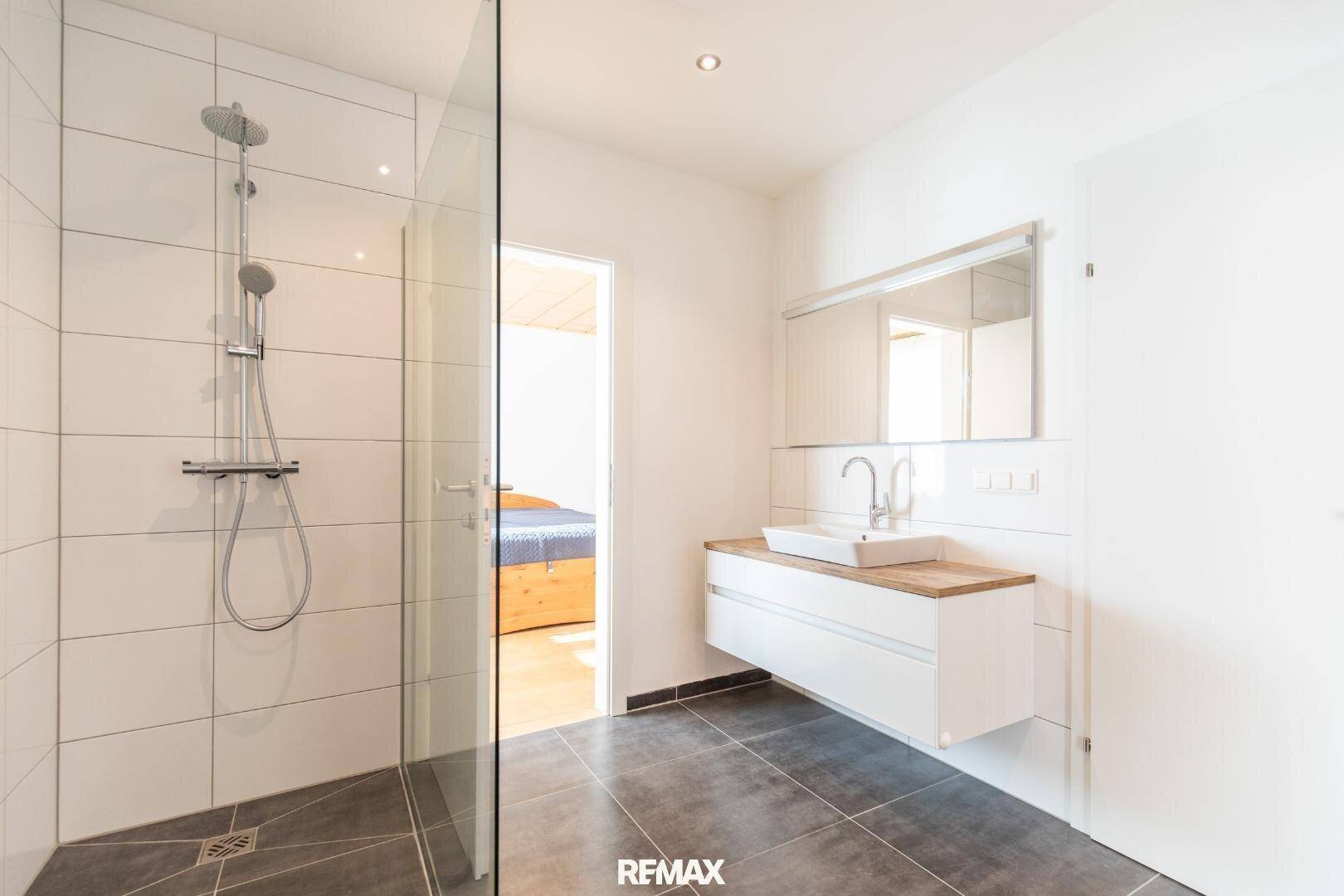 Helles Badezimmer mit begehbarer Dusche, modernem Waschtisch und weißen Wandfliesen.