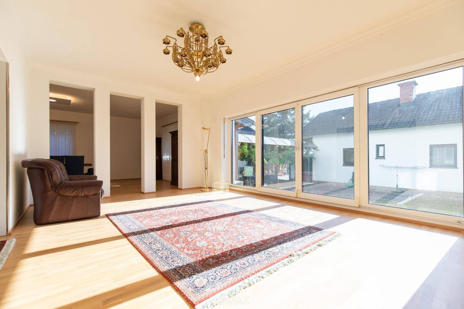 Helles Wohnzimmer mit großen Schiebetüren, Parkettboden und einem orientalischen Teppich.