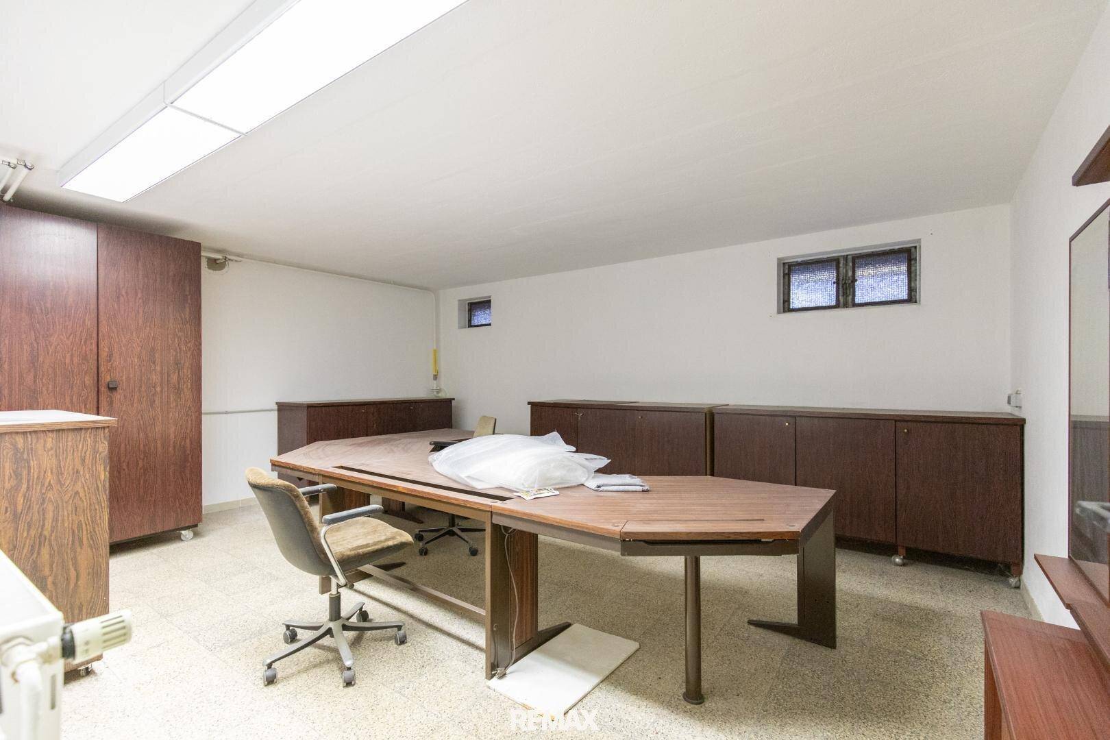 Geräumiger Kellerraum mit großem Schreibtisch und Schränken, nutzbar als Büro oder Hobbyraum.