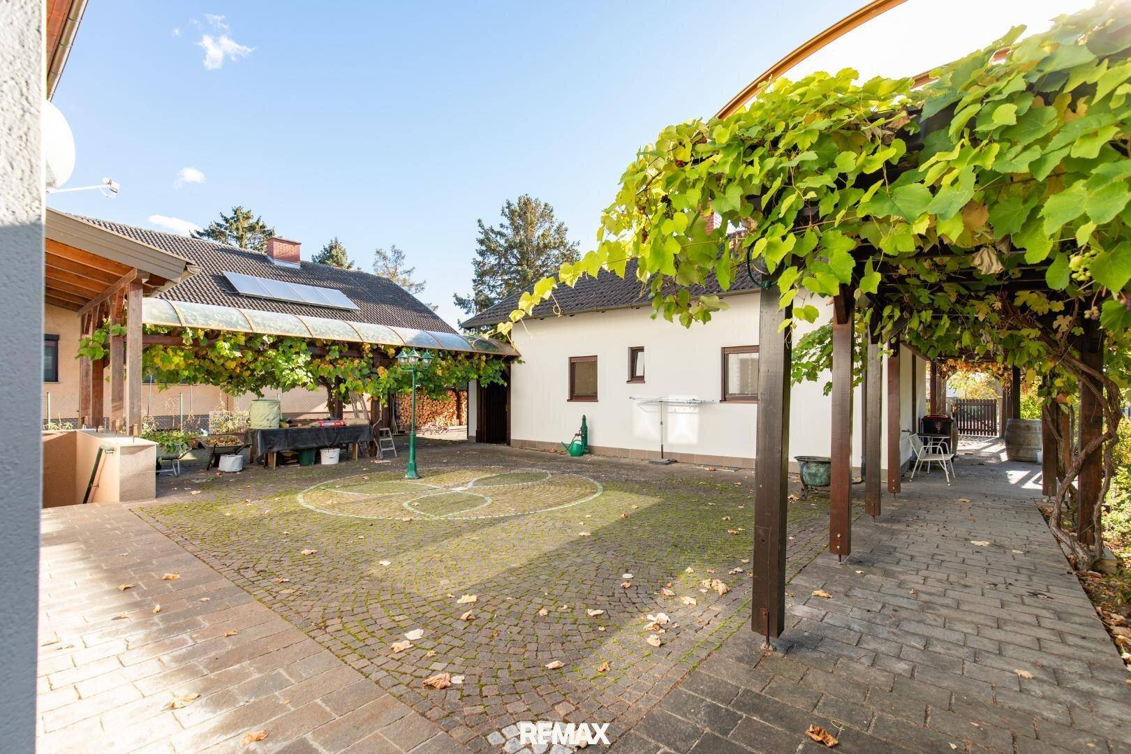 Gepflasterter Innenhof mit bewachsener Pergola, bietet einen schattigen Außenbereich.
