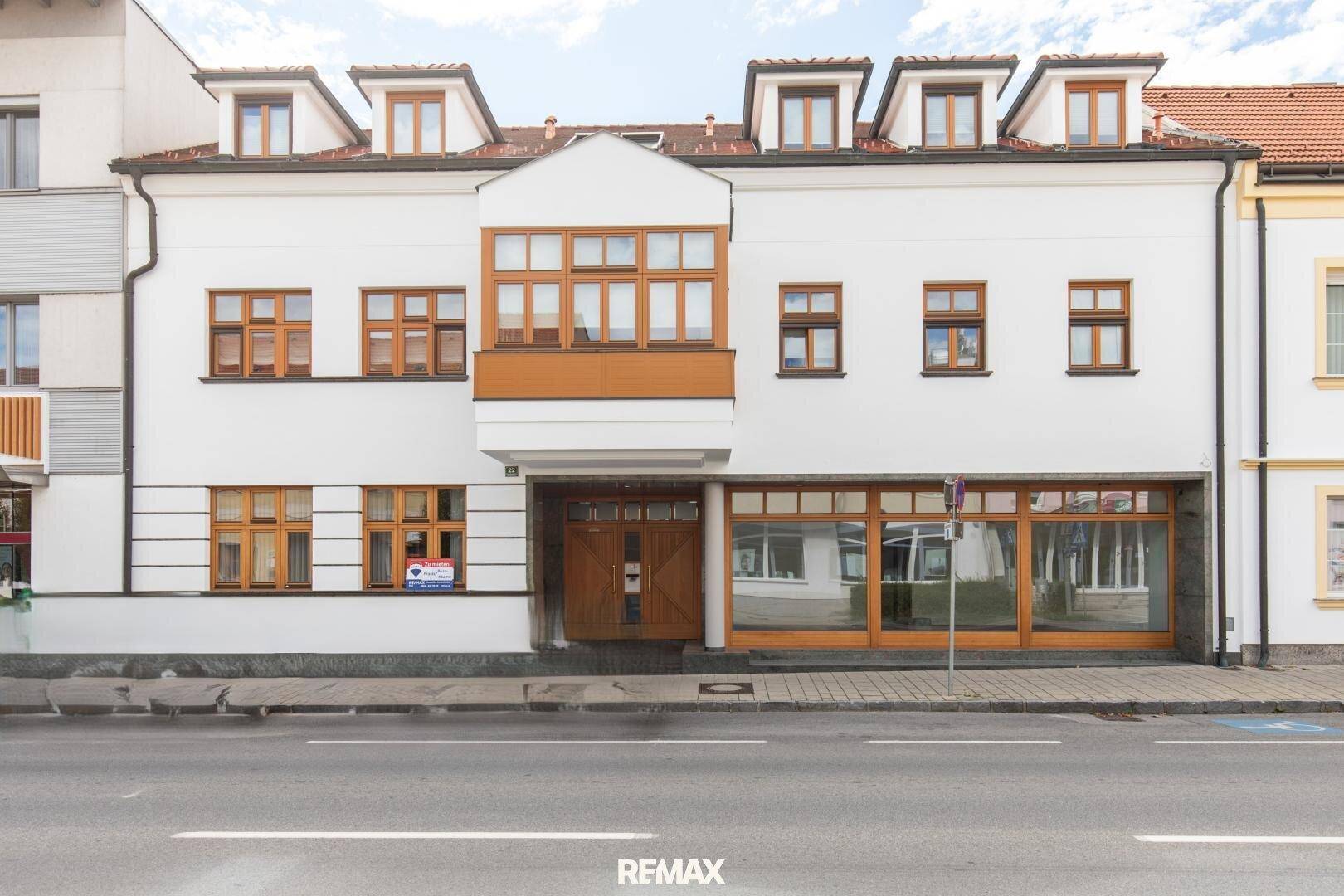 Historisches Gebäude mit weißer Fassade, vielen Fenstern und Holzelementen an der Straße gelegen.