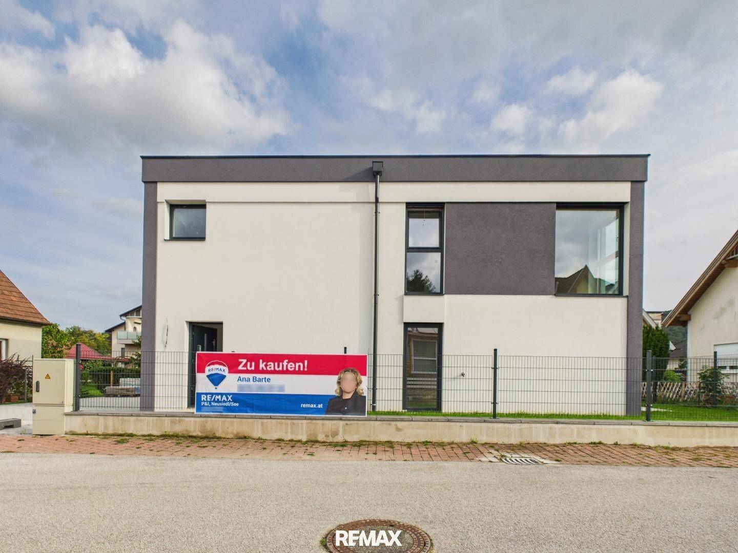 Moderne Hausfassade mit großen Fenstern und einem 