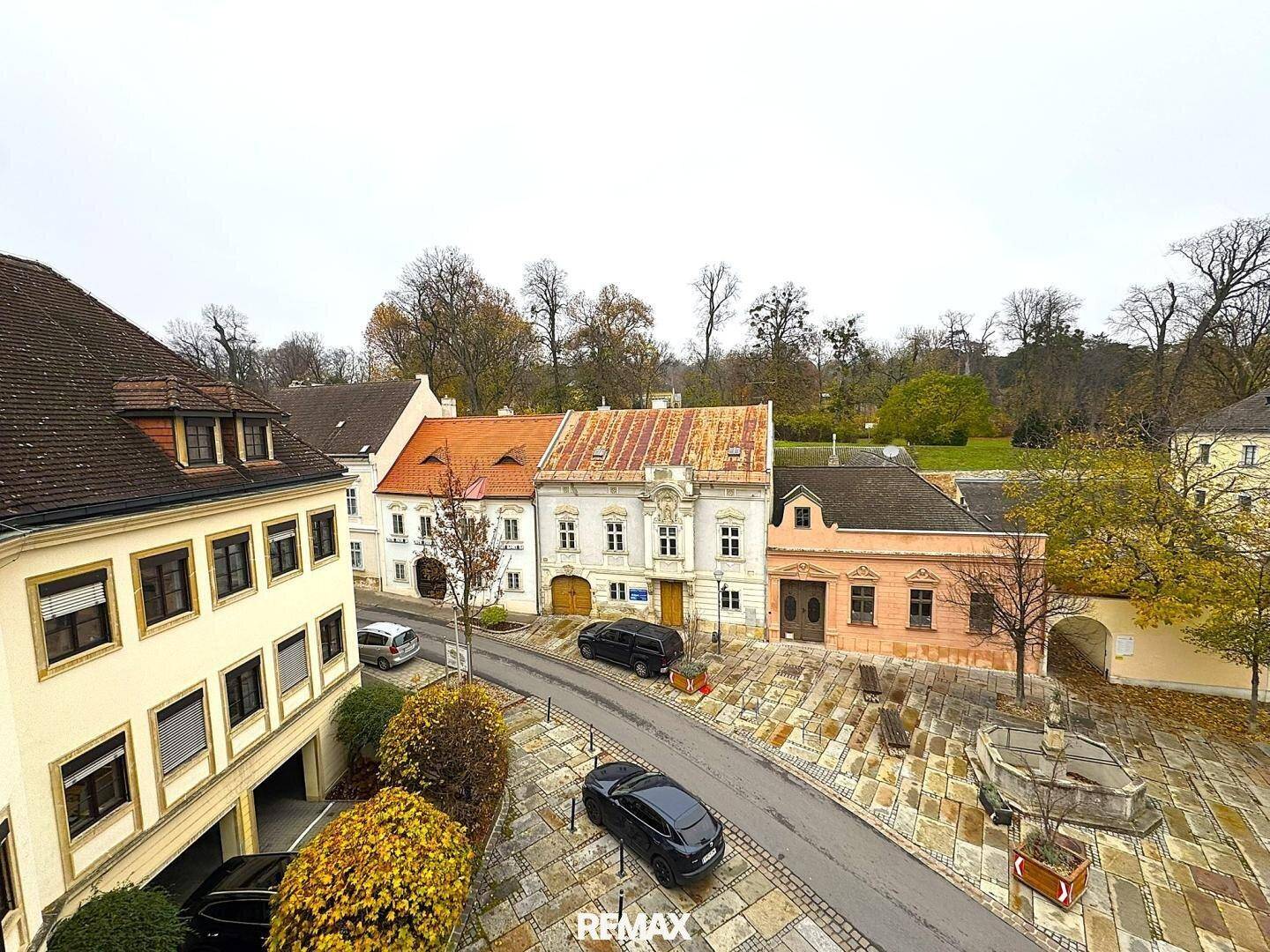Blick von oben auf eine historische Straße mit geparkten Autos und alten Gebäuden.