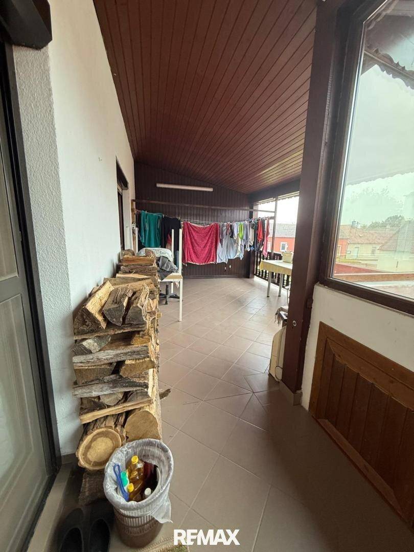 Überdachte Loggia mit Fliesenboden, Holzdecke und Wäscheleine, ideal für den Alltag.