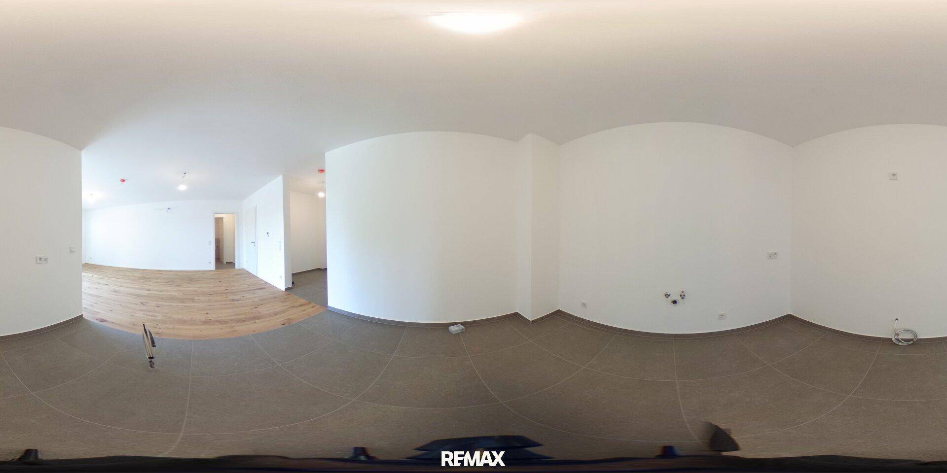 Panoramaansicht des offenen Wohnbereichs mit Holzboden und angrenzendem Fliesenbereich.