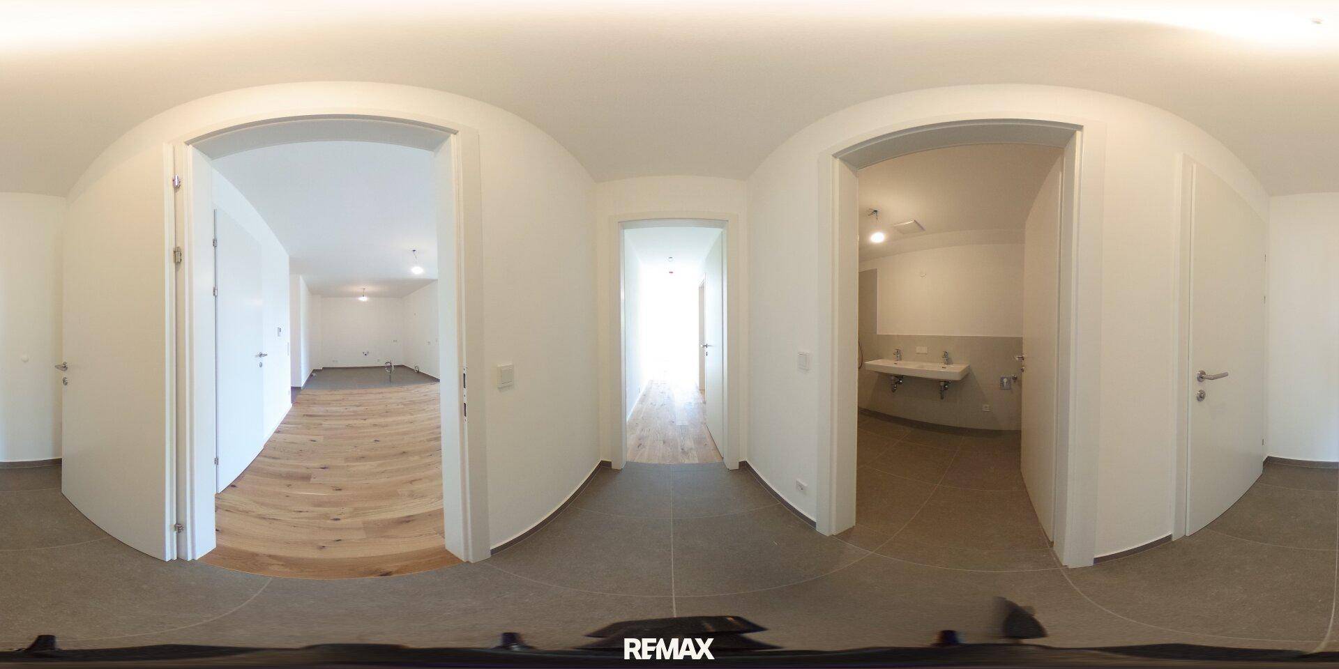 Panoramaansicht eines Flurs mit Fliesenboden, der zu verschiedenen Zimmern führt.