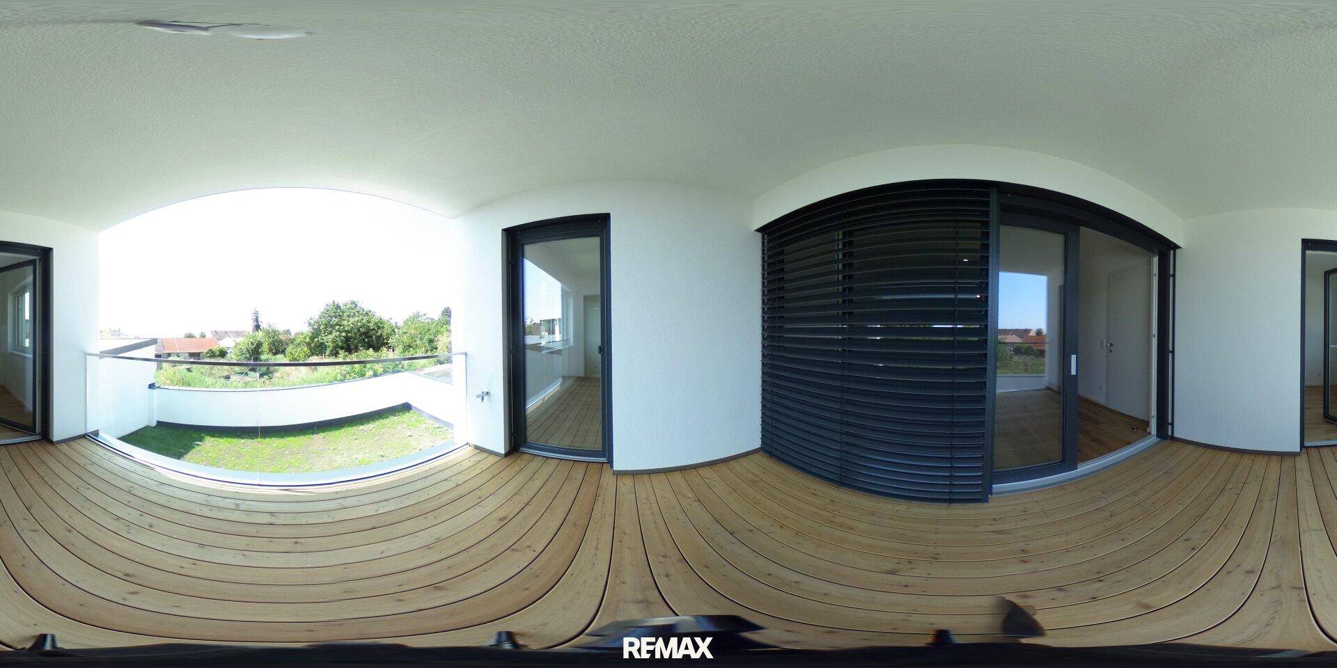 Großer Balkon mit Holzbelag, Glasgeländer und Schiebetüren zum Innenbereich mit Rollläden.