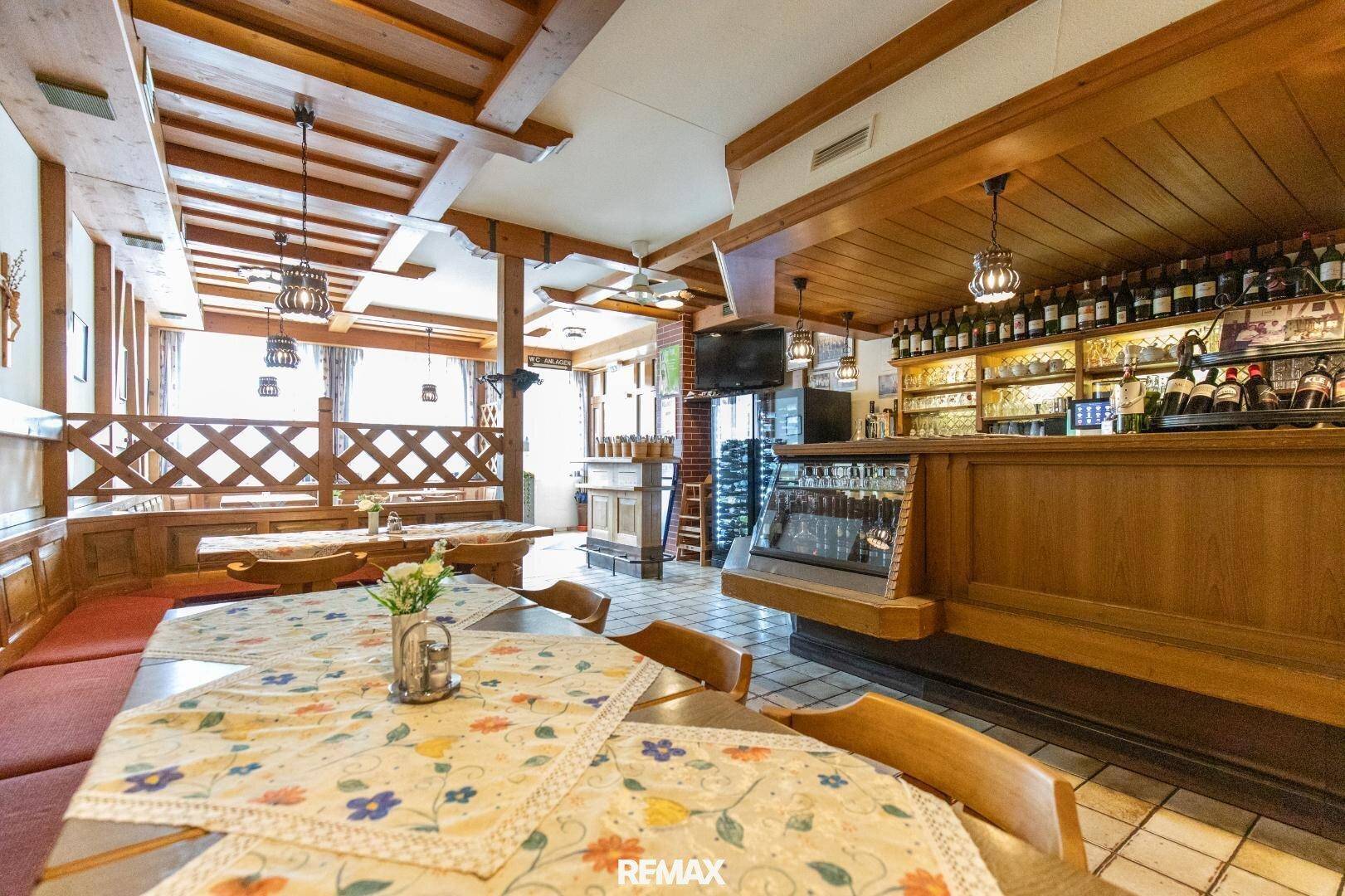 Gemütlicher Restaurantbereich mit traditioneller Holzvertäfelung, Holzbalkendecke und einer gut bestückten Bar.