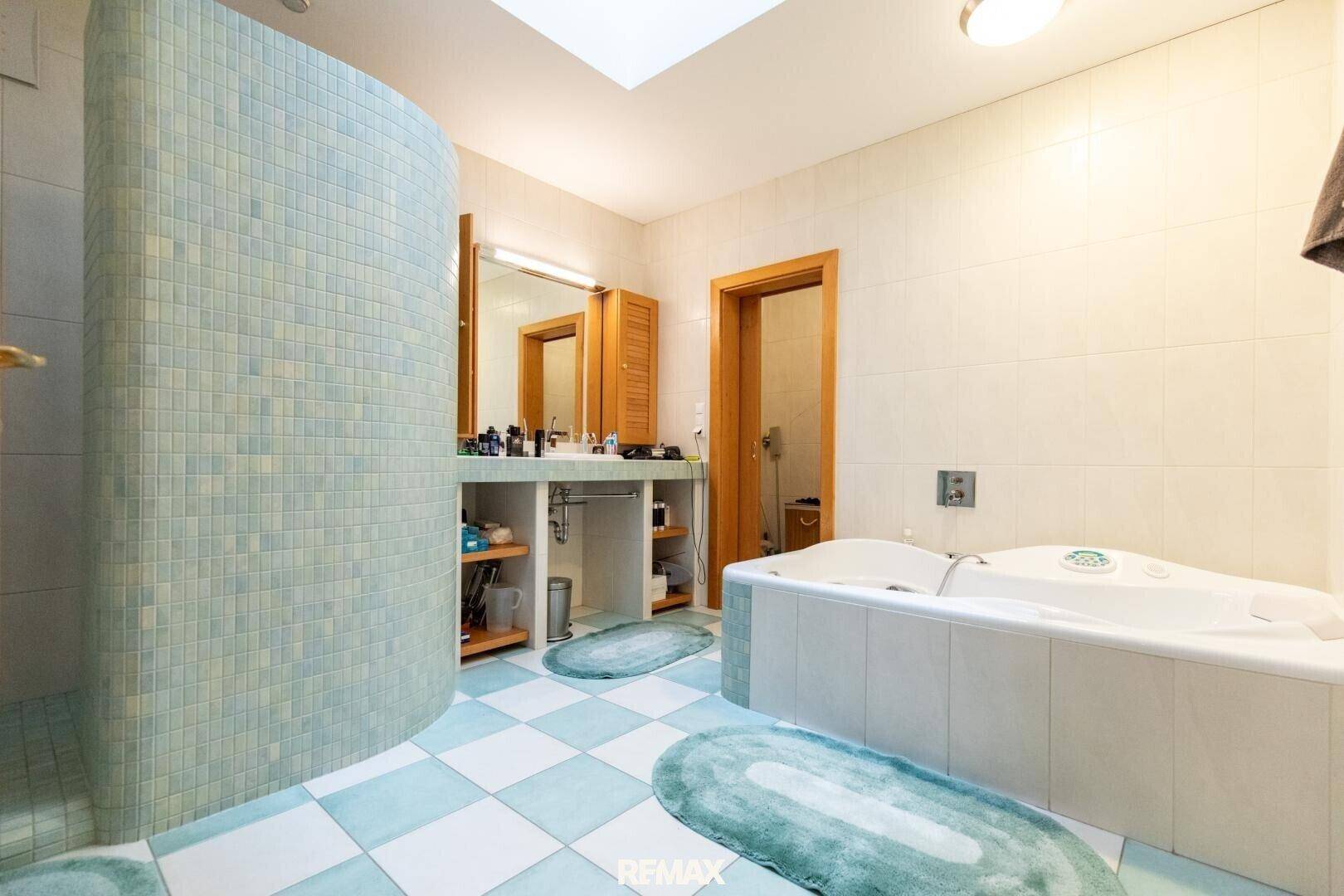 Modernes Badezimmer mit großer Badewanne, Doppelwaschtisch und auffälligen blau-weißen Fliesen.