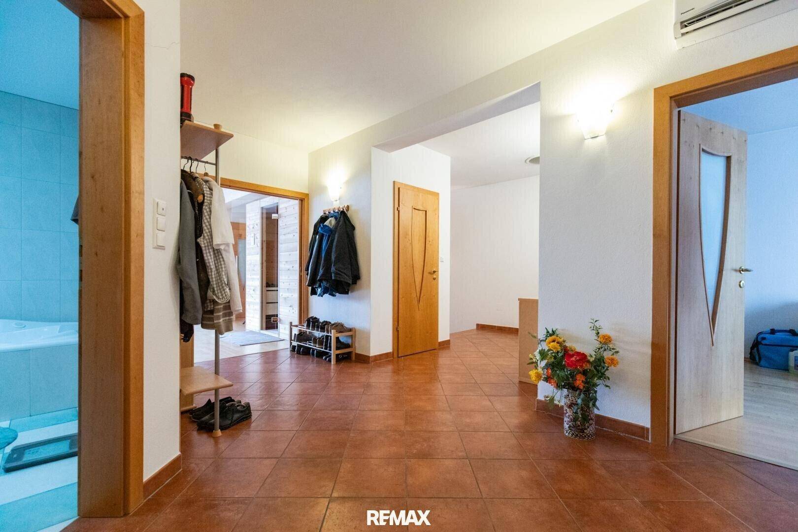 Heller Flur mit Terrakotta-Fliesenboden, Garderobe und Zugang zu verschiedenen Räumen.