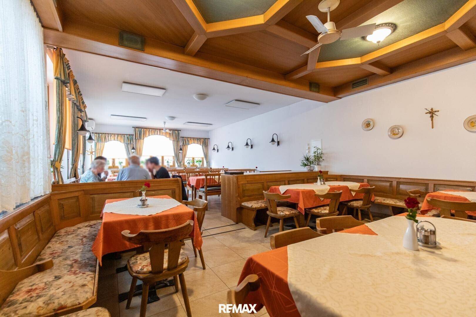 Geräumiger Restaurantbereich mit rustikalen Holzbänken und Tischen, ergänzt durch eine Holzbalkendecke.