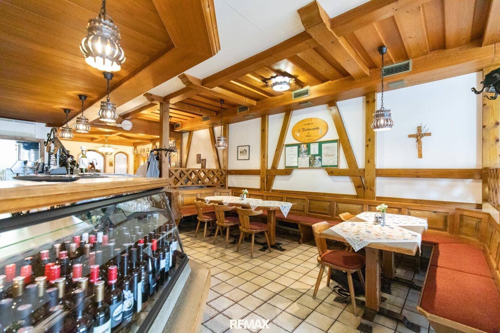 Traditioneller Barbereich eines Restaurants mit Holzeinrichtung, gefliestem Boden und einer Auswahl an Getränken.