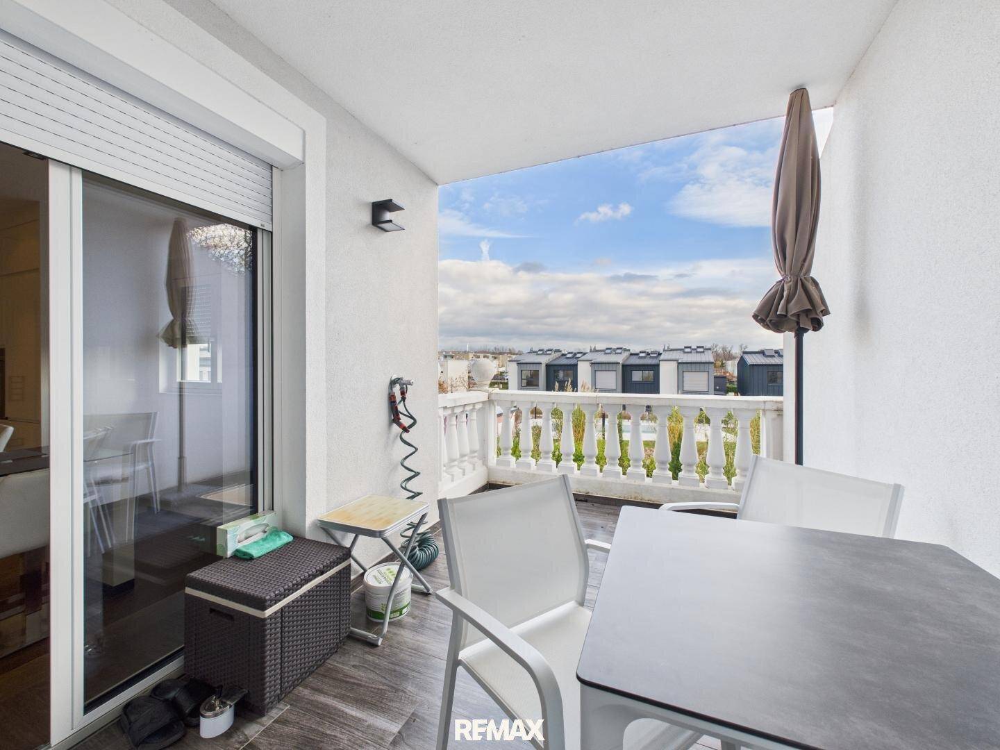 Heller Balkon mit Sitzgelegenheiten, Balustrade und Blick auf die Umgebung.
