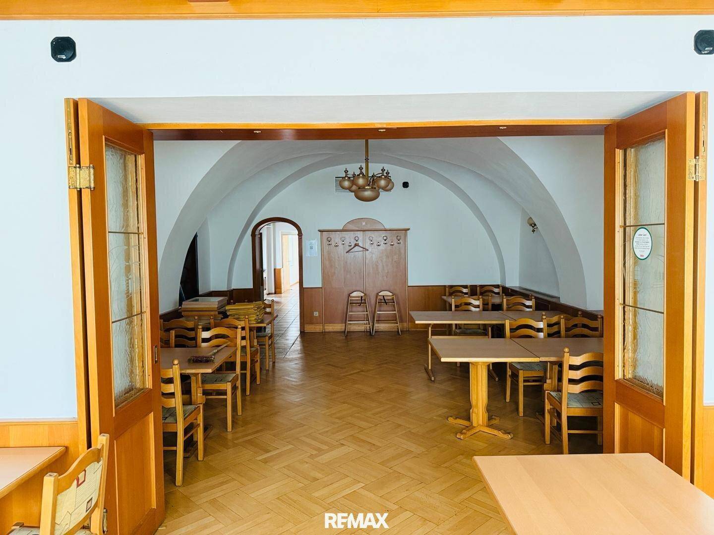 Großer Speisesaal mit Gewölbedecke, Fischgrätparkett und Holztischen mit Stühlen.