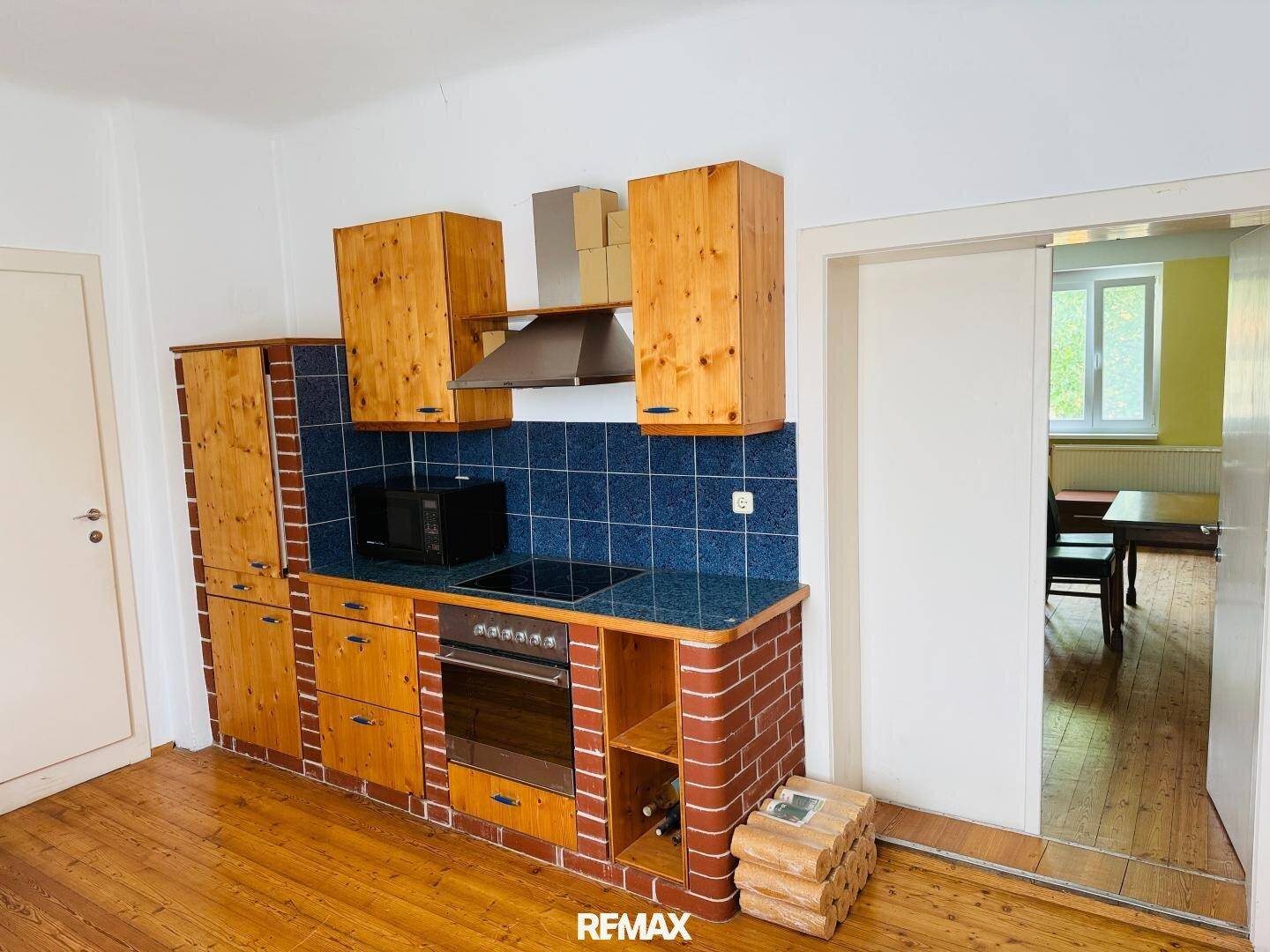 Rustikale Küche mit Holzschränken, blauen Fliesen und eingebauten Geräten.