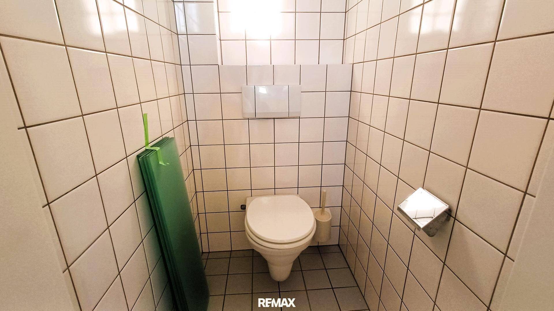 Kleiner Toilettenraum mit weißen Fliesen an Wänden und Boden, ausgestattet mit WC.