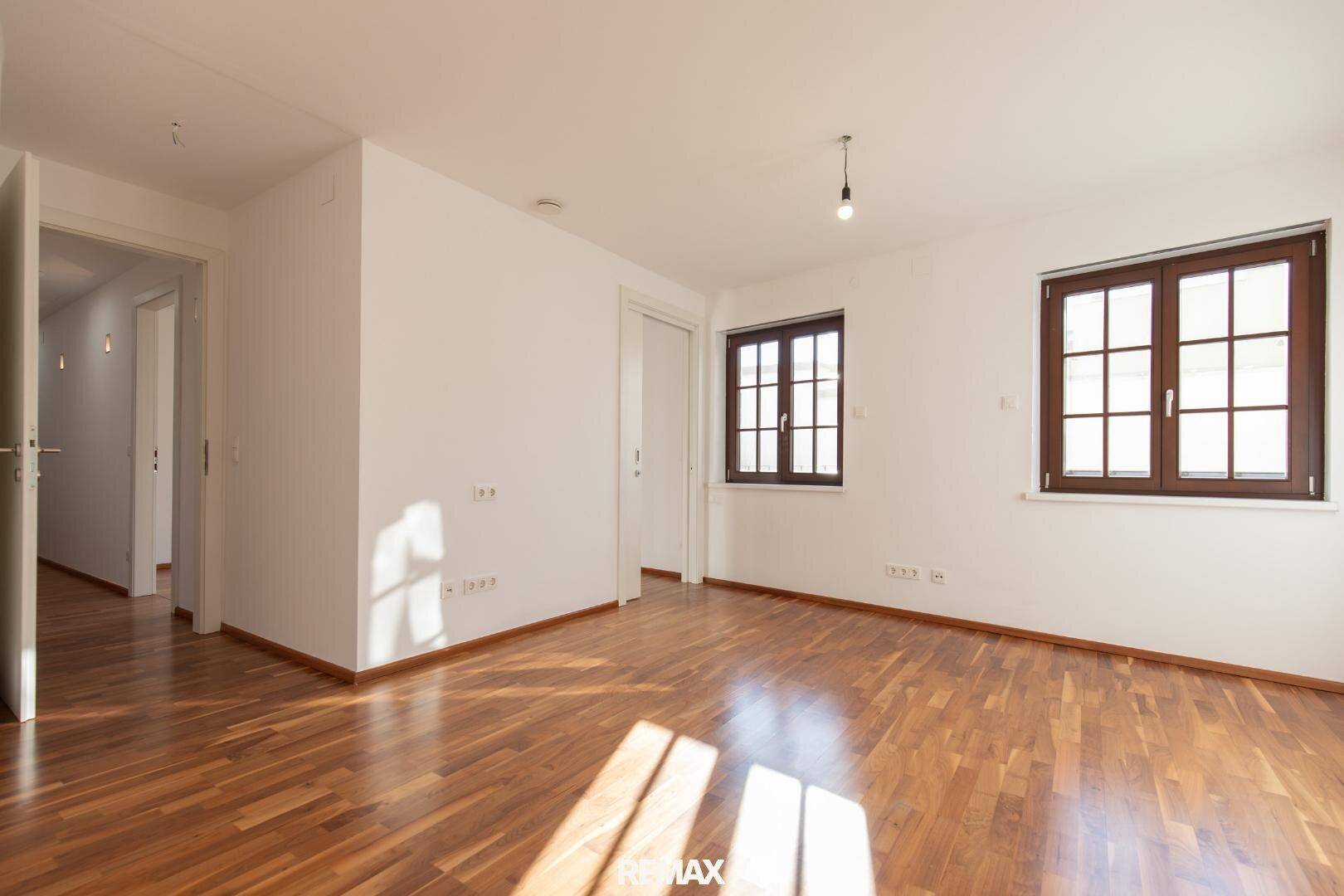Helles Zimmer mit Parkettboden und zwei Fenstern, bietet viel Tageslicht.