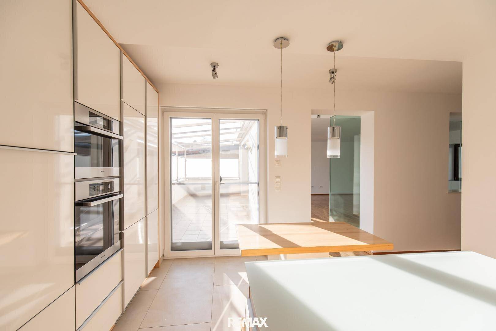 Helle Küche mit Zugang zur Terrasse, integrierten Öfen und modernem Design.