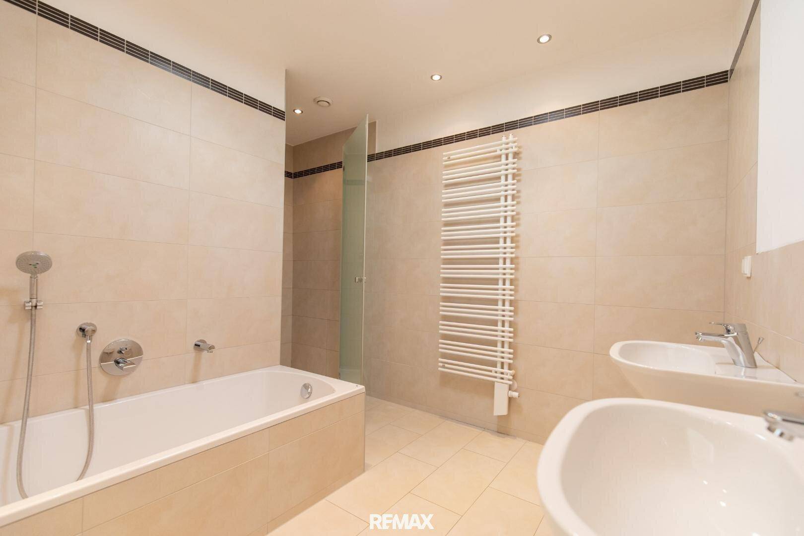 Modernes Badezimmer mit Badewanne, Dusche, Doppelwaschbecken und beheiztem Handtuchhalter.