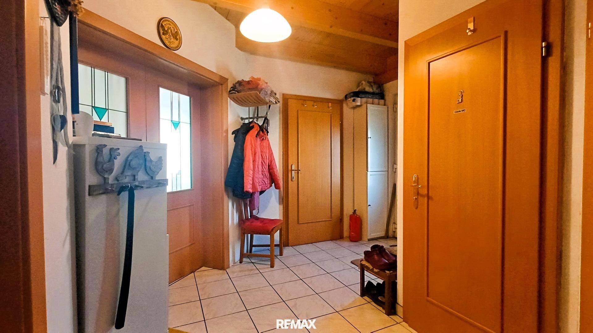 Gemütlicher Eingangsbereich mit Holzdecke, Fliesenboden und Garderobe, der zu weiteren Räumen führt.