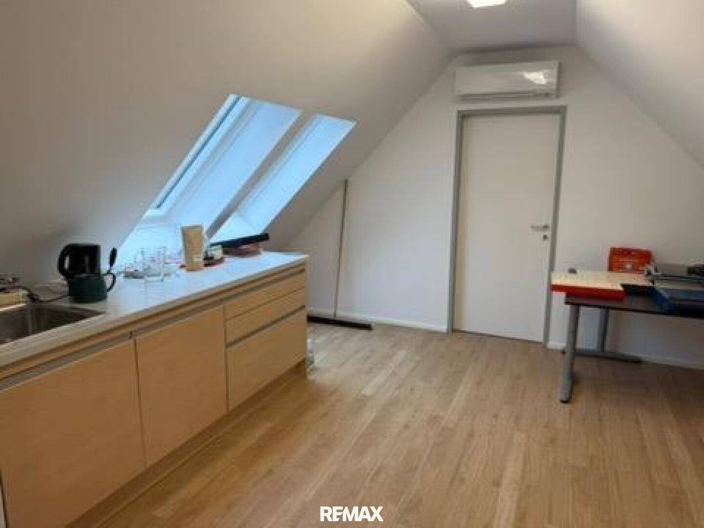 Kleine Küchenzeile im Dachgeschoss mit Spüle, Arbeitsplatte und Dachfenstern.